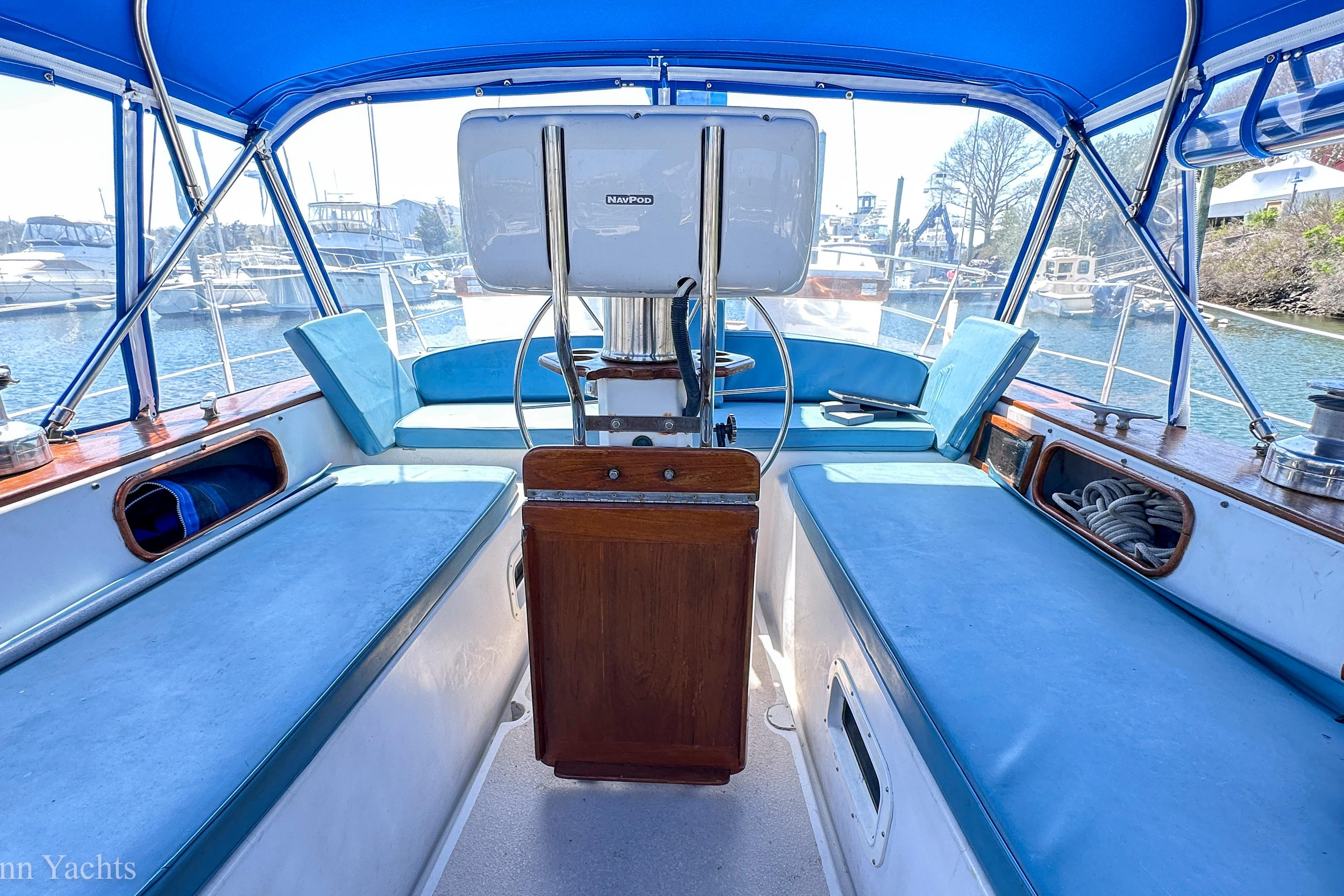 Cockpit of 1980 Irwin 46 sailboat with blue canopy and seating, docked in marina.