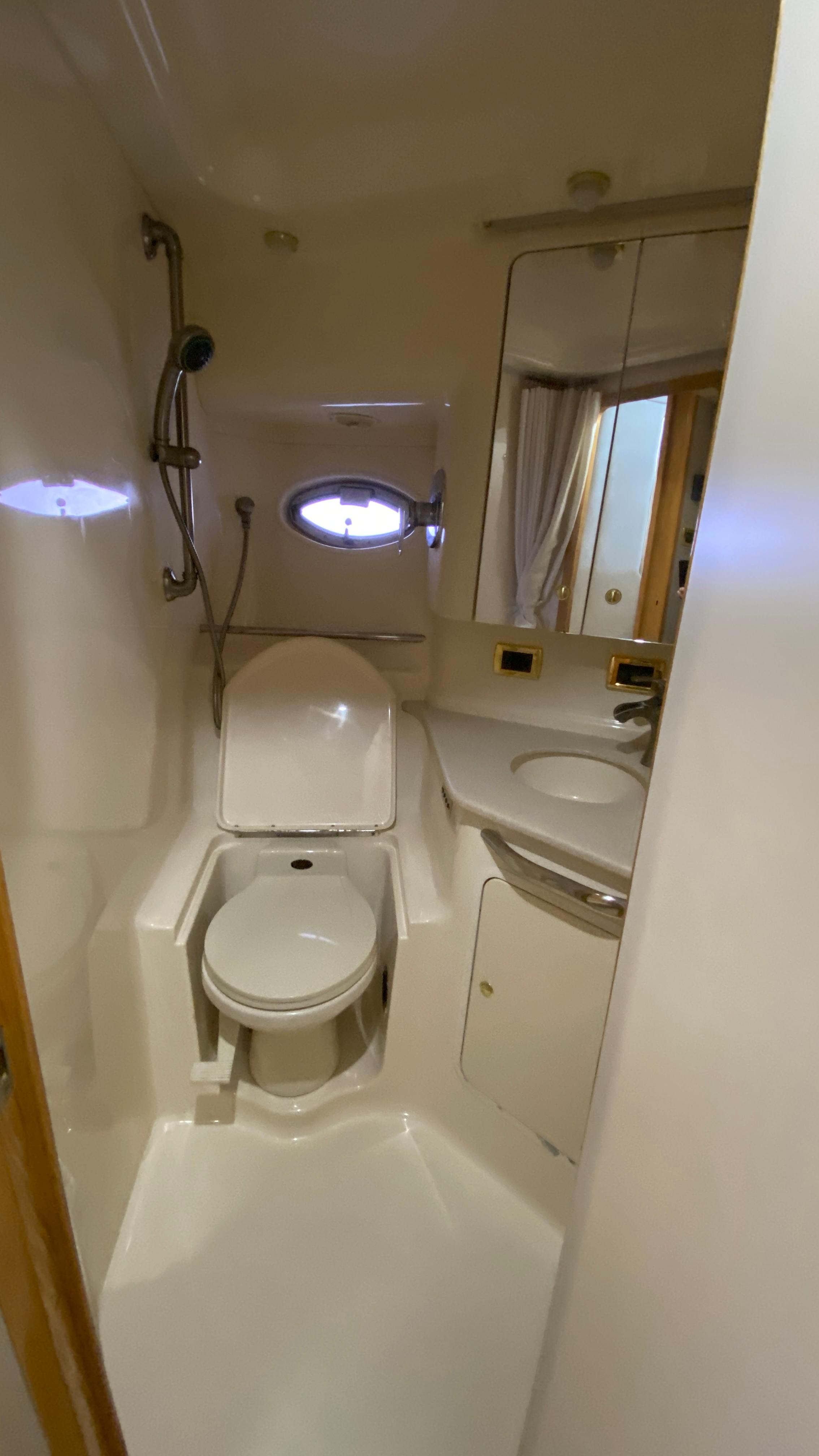 Compact bathroom in 2001 Sea Ray 460 Sundancer yacht with toilet, sink, and shower.
