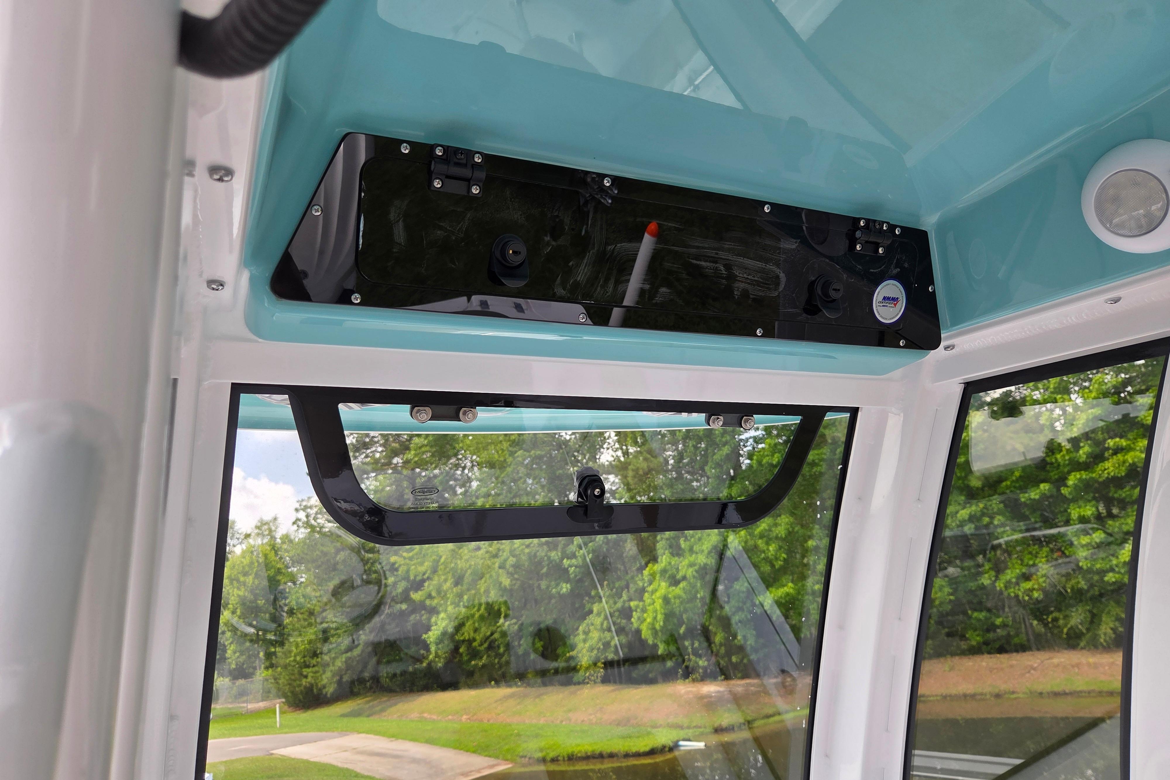 Interior view of 2026 Sportsman Open 232 Center Console boat, featuring overhead storage and windows.