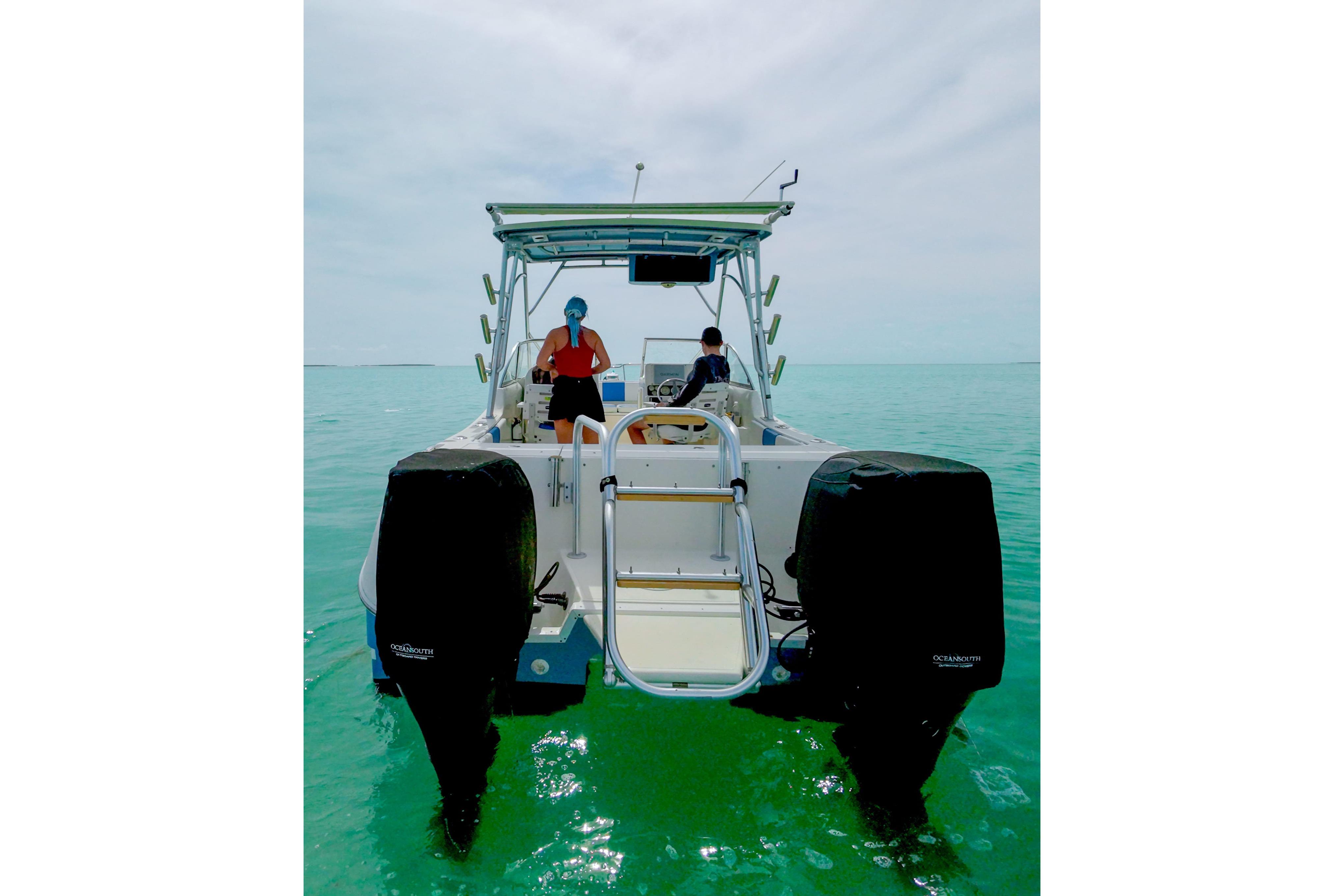 2006 World Cat 250 DC boat on clear turquoise water, rear view with two people onboard.