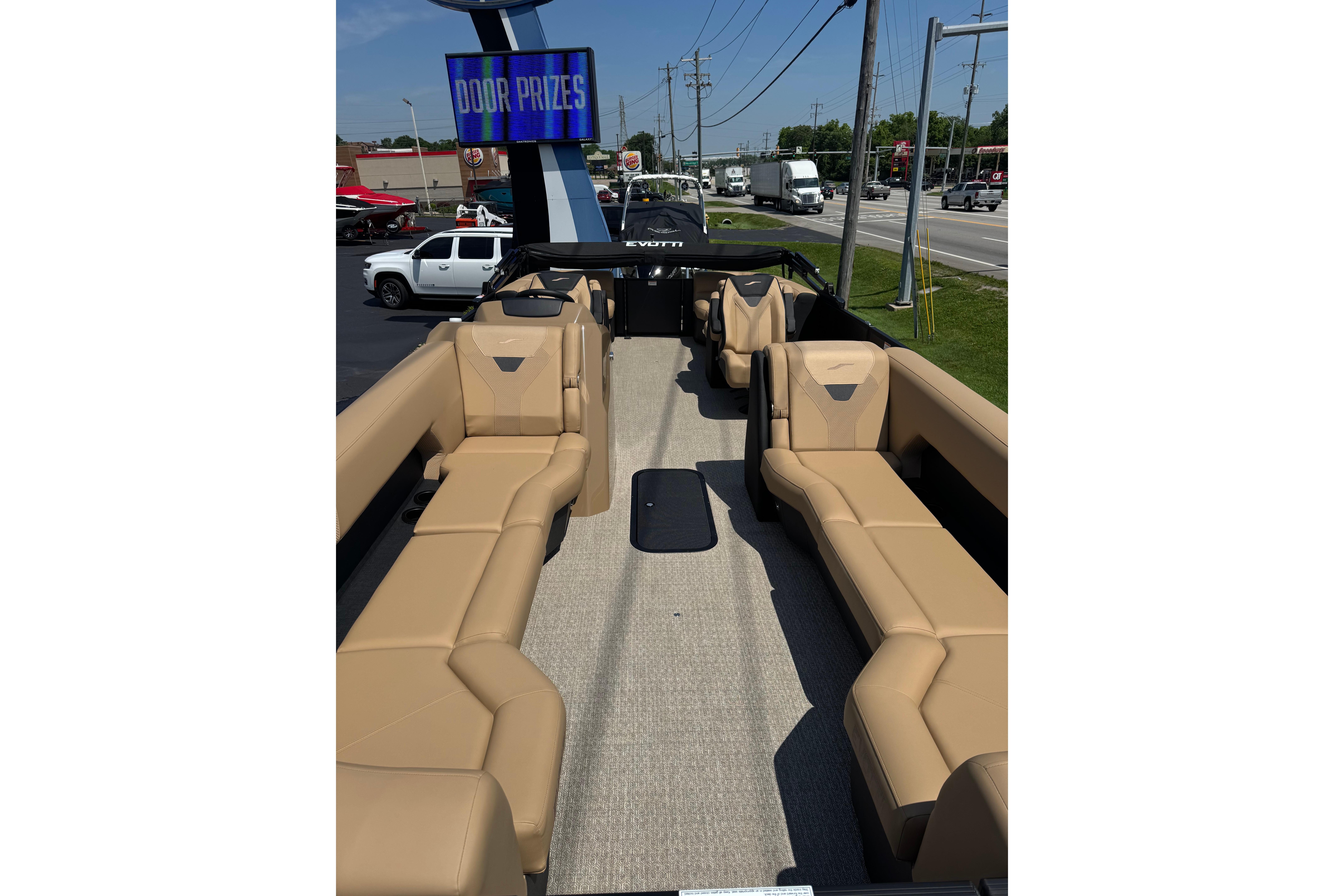 2026 Evotti 525QL boat interior with tan seating, displayed outdoors near a road.