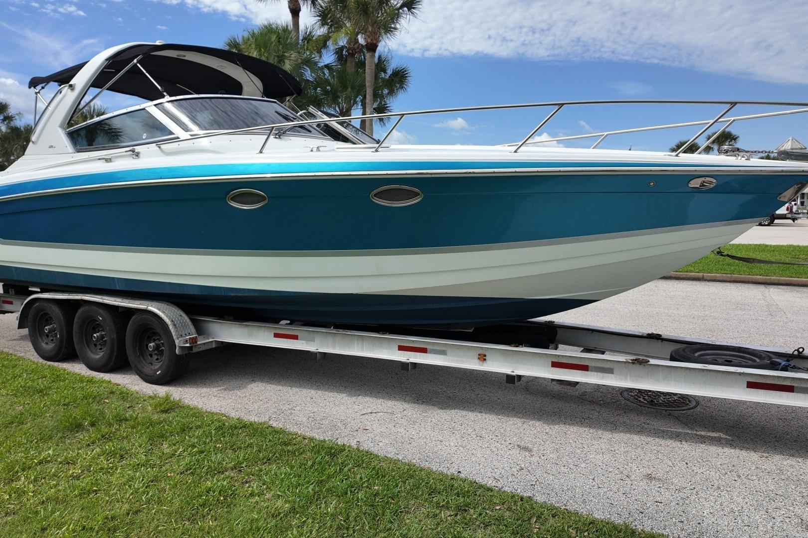 2007 Formula 330 Sun Sport boat on trailer, parked outdoors under blue sky.