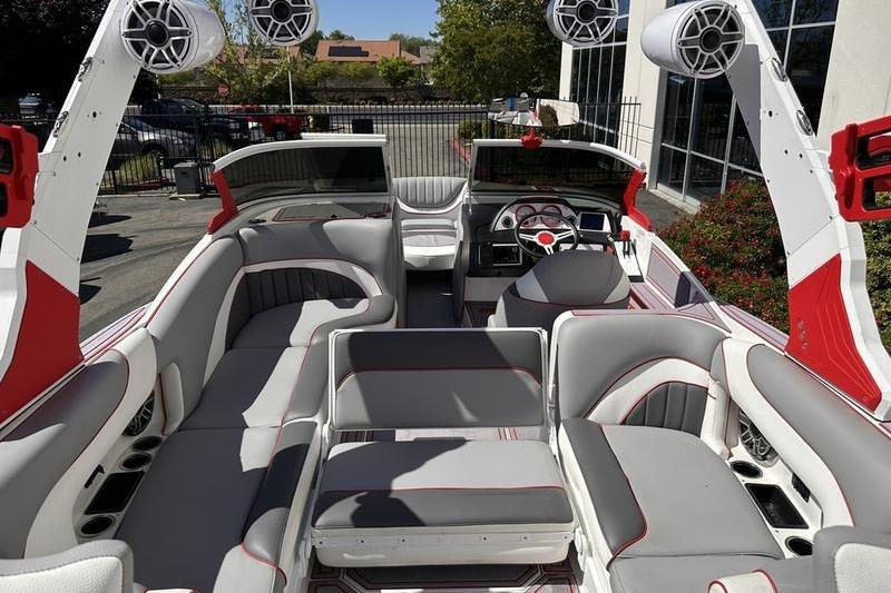 2023 MB SPORTS F22 Tomcat Alpha boat interior with red and gray seating, speakers, and dashboard.