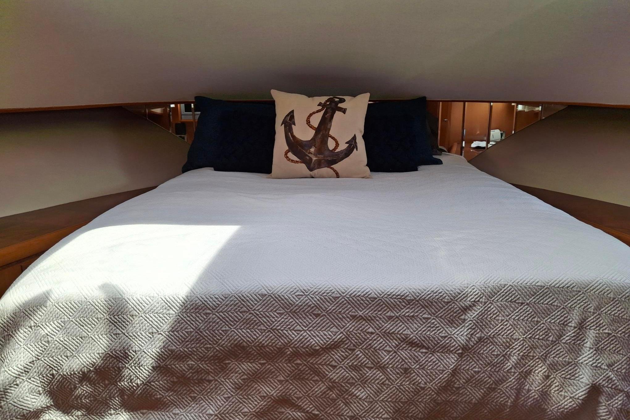 Cozy bedroom in 2004 Ocean Alexander 64 Pilothouse with anchor-themed decor.