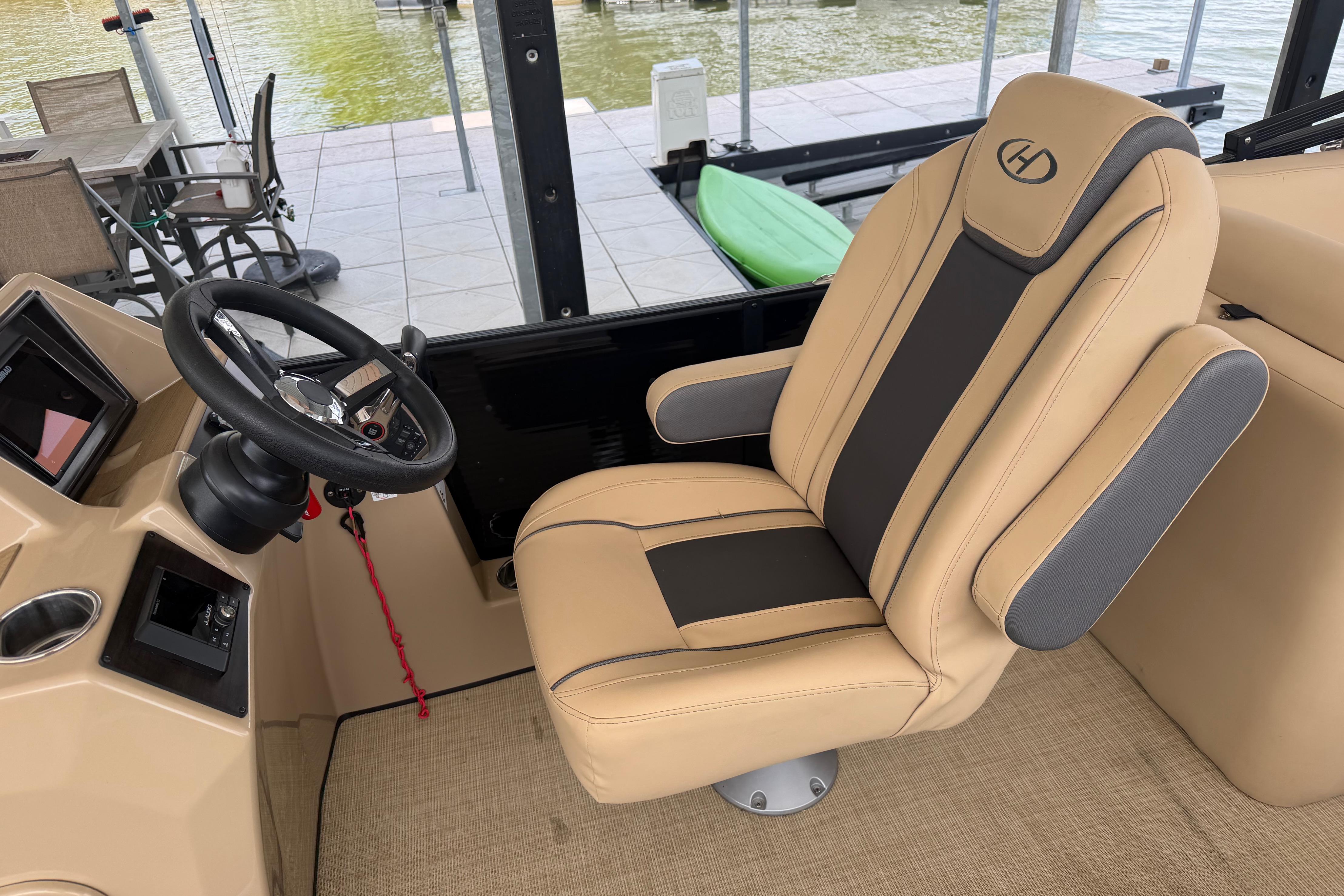 2023 Harris Cruiser 250 CW boat interior with beige captain's chair and steering wheel.
