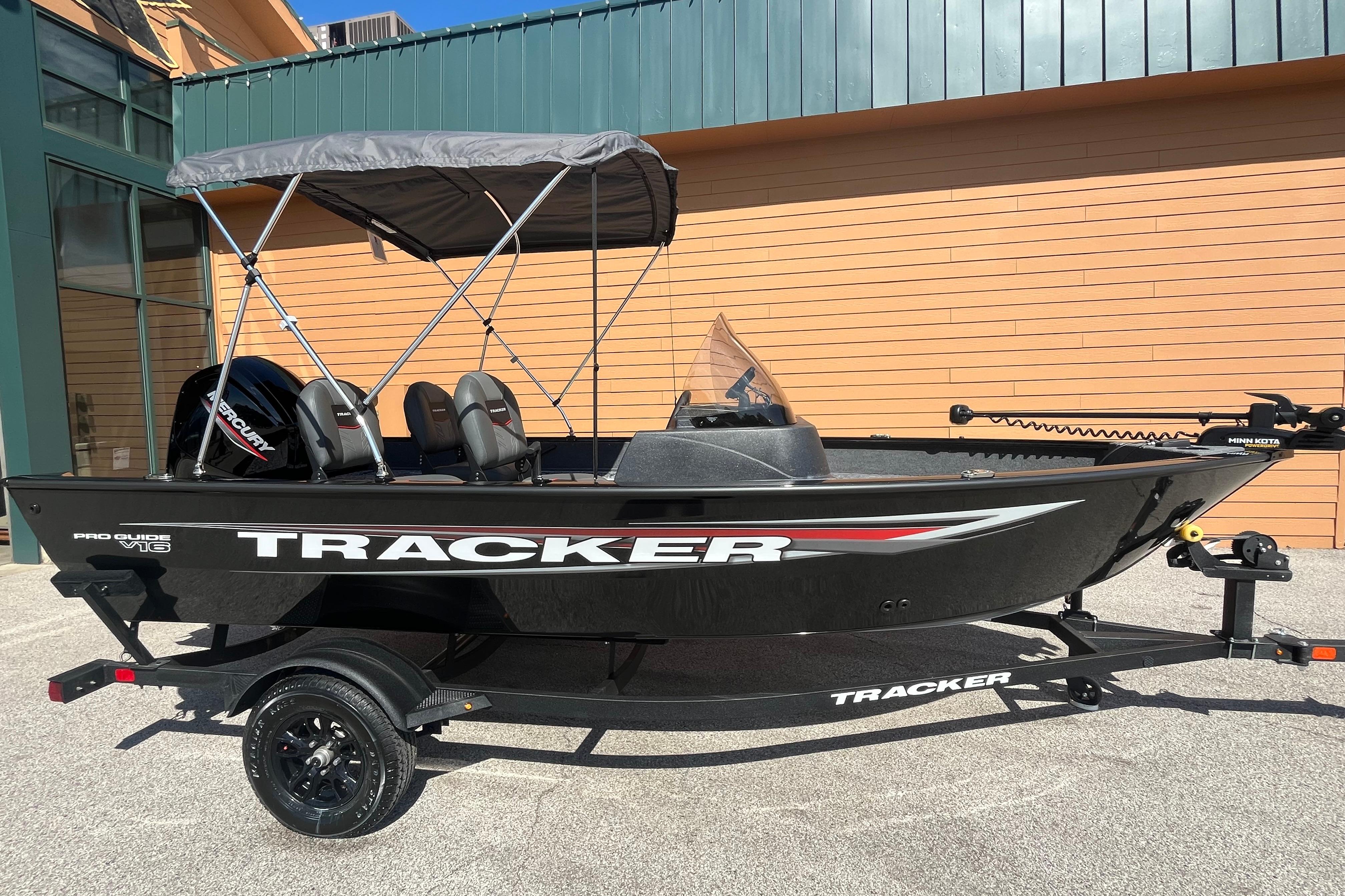 2026 Tracker Pro Guide V-16 SC boat with canopy, displayed outdoors on a trailer.