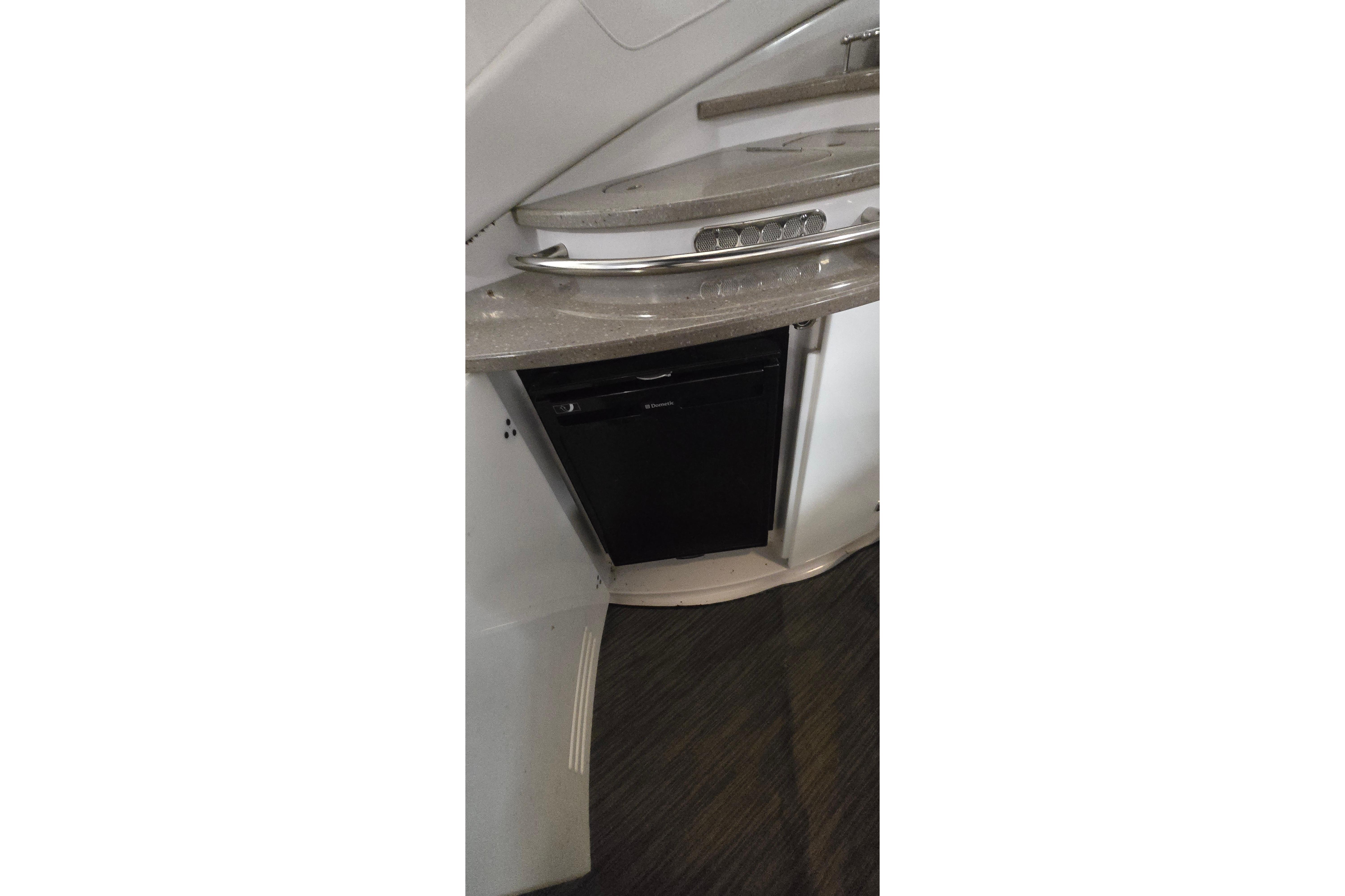 2018 Four Winns V355 yacht kitchenette with compact fridge and sleek countertop design.