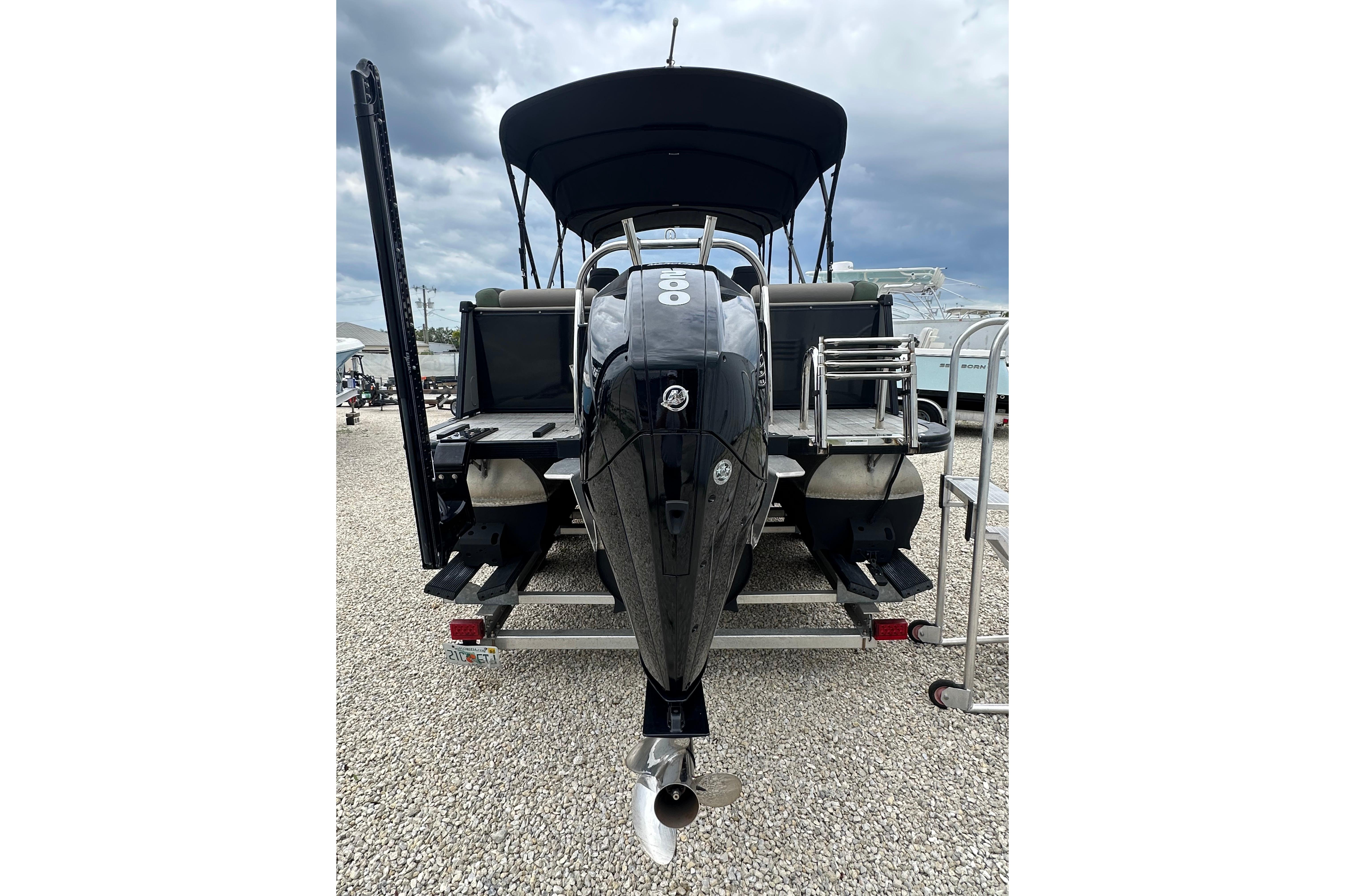 2023 Avalon Catalina Quad Lounge 23' pontoon boat with powerful outboard motor, parked on gravel.