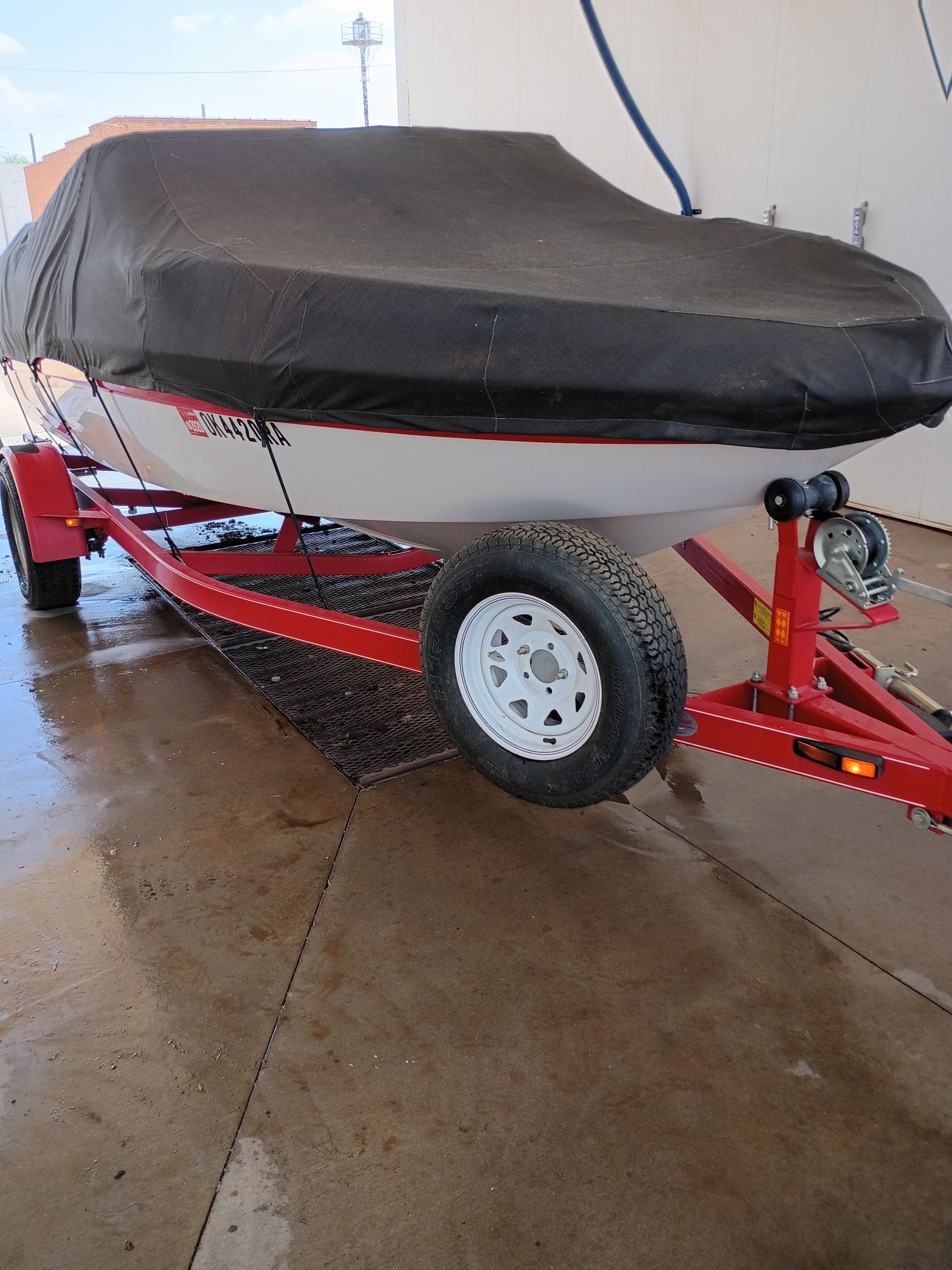 2010 Glastron MX 185 boat on red trailer with cover.