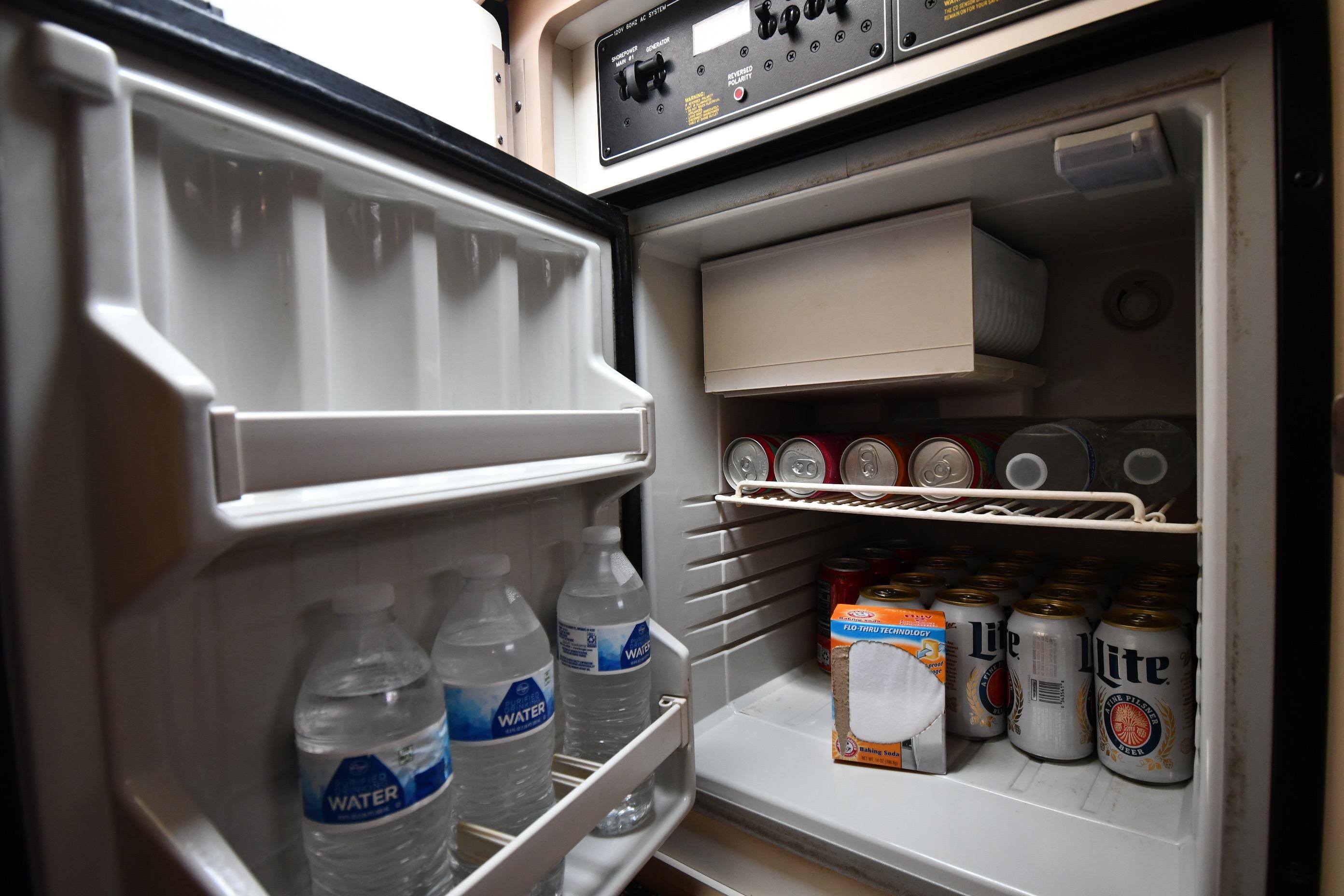 Mini fridge stocked with drinks and water bottles on a 2004 Formula 330 Sun Sport boat.