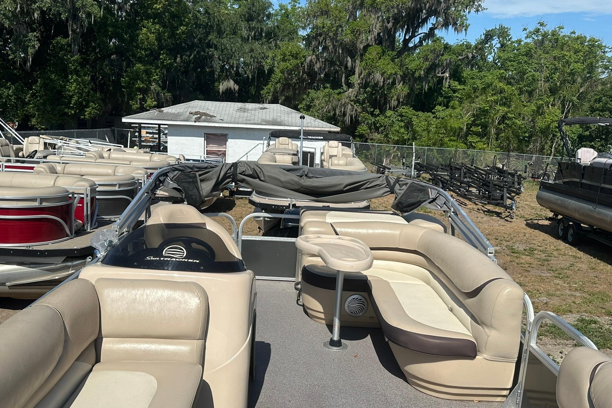 2016 SUNTRACKER Party Barge 20 pontoon boat with beige seating, parked outdoors.