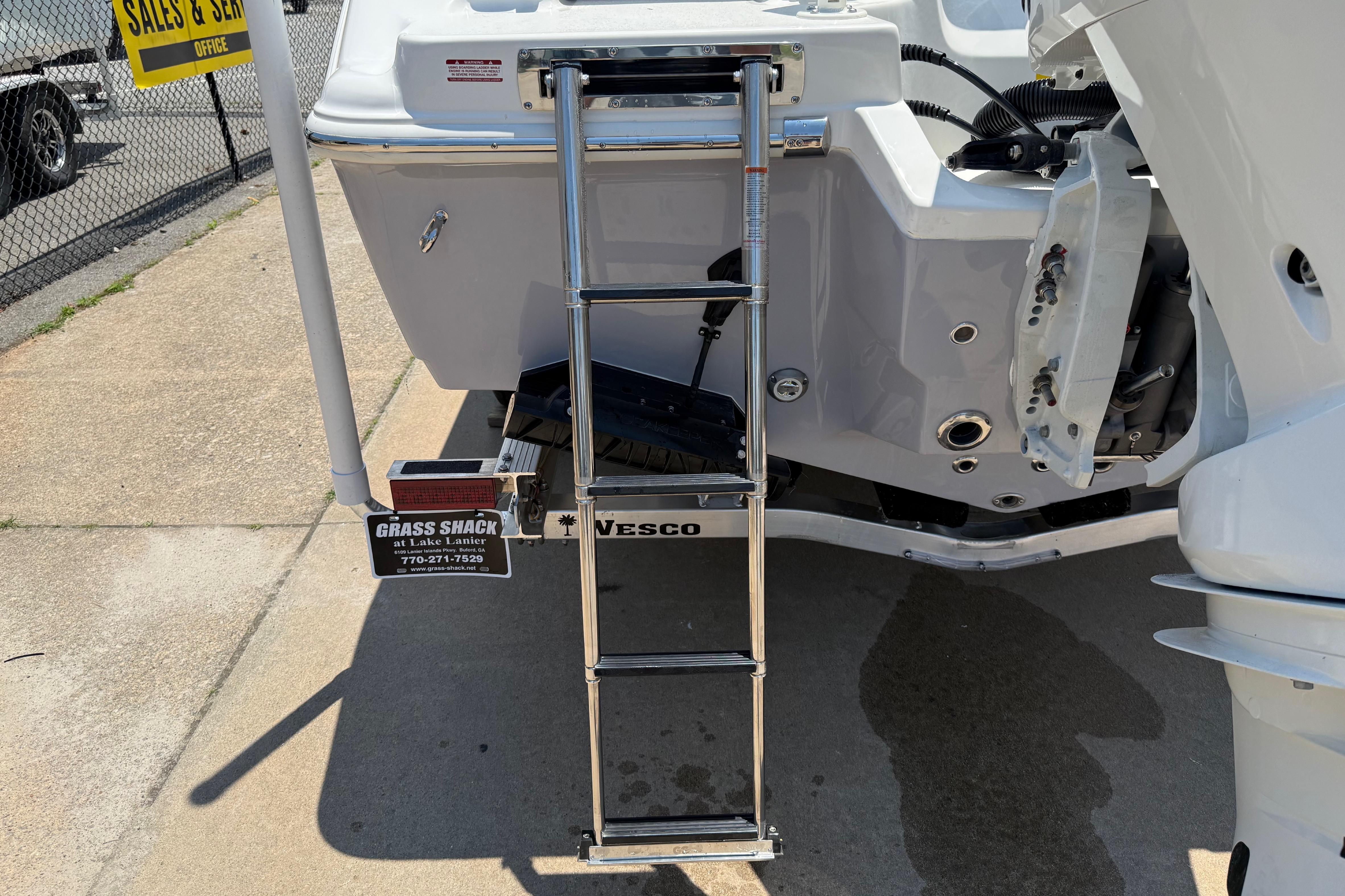 2027 Key West 249 FS boat with ladder and motor, displayed at a sales and service location.
