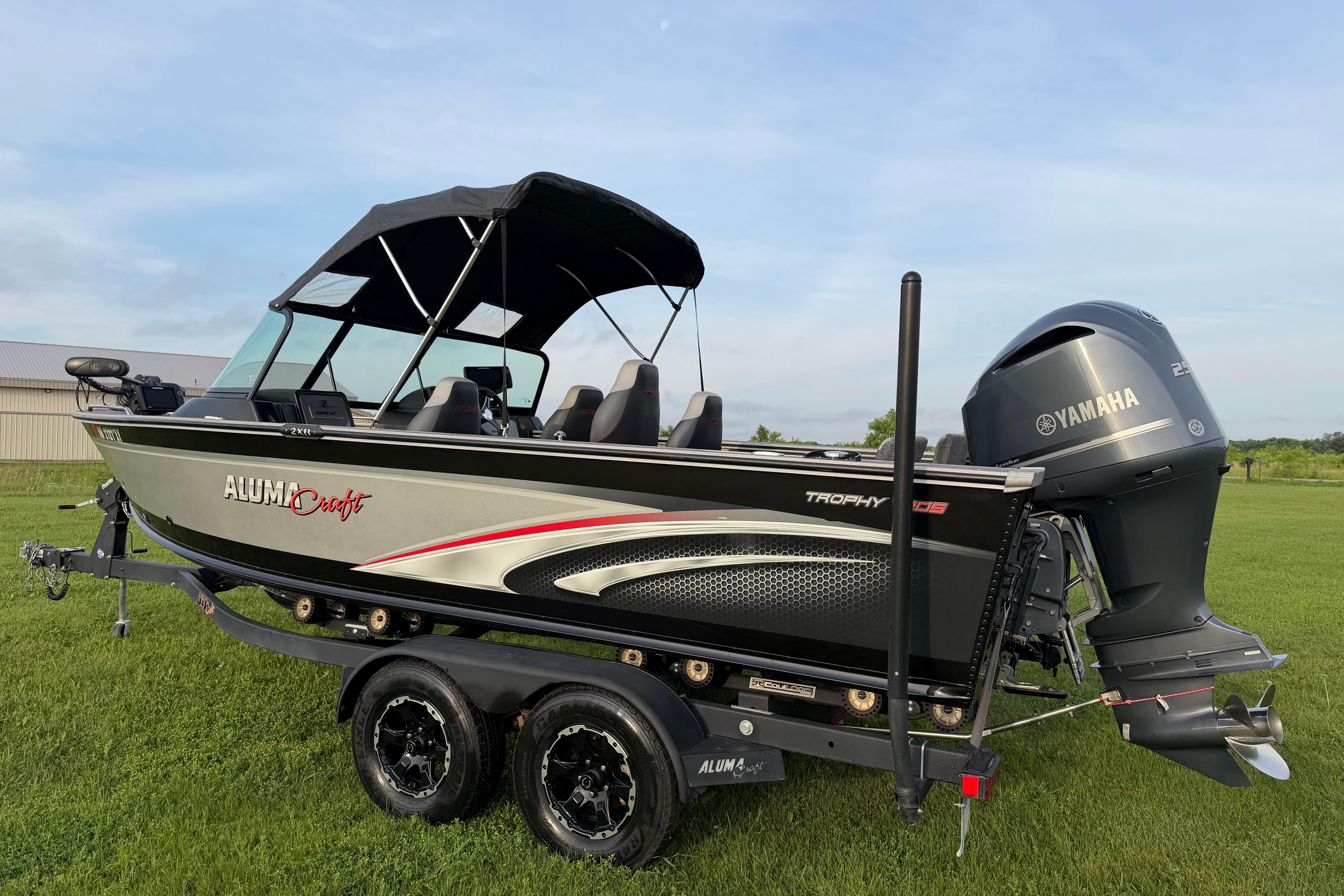2019 Alumacraft Trophy 205 boat with Yamaha engine on a trailer, parked on grass.