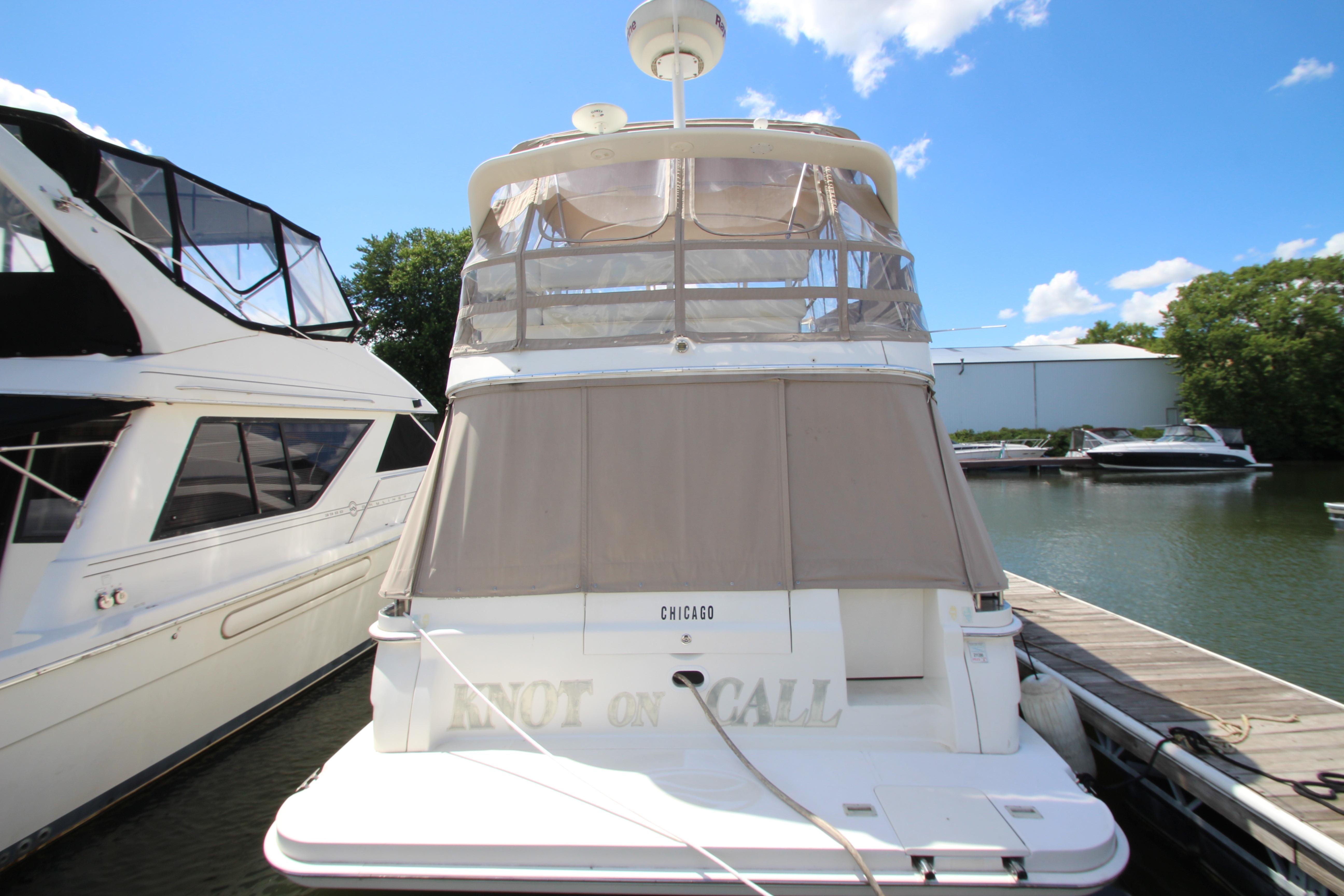 2006 Silverton 38 Sport Bridge yacht docked at marina under clear blue sky.