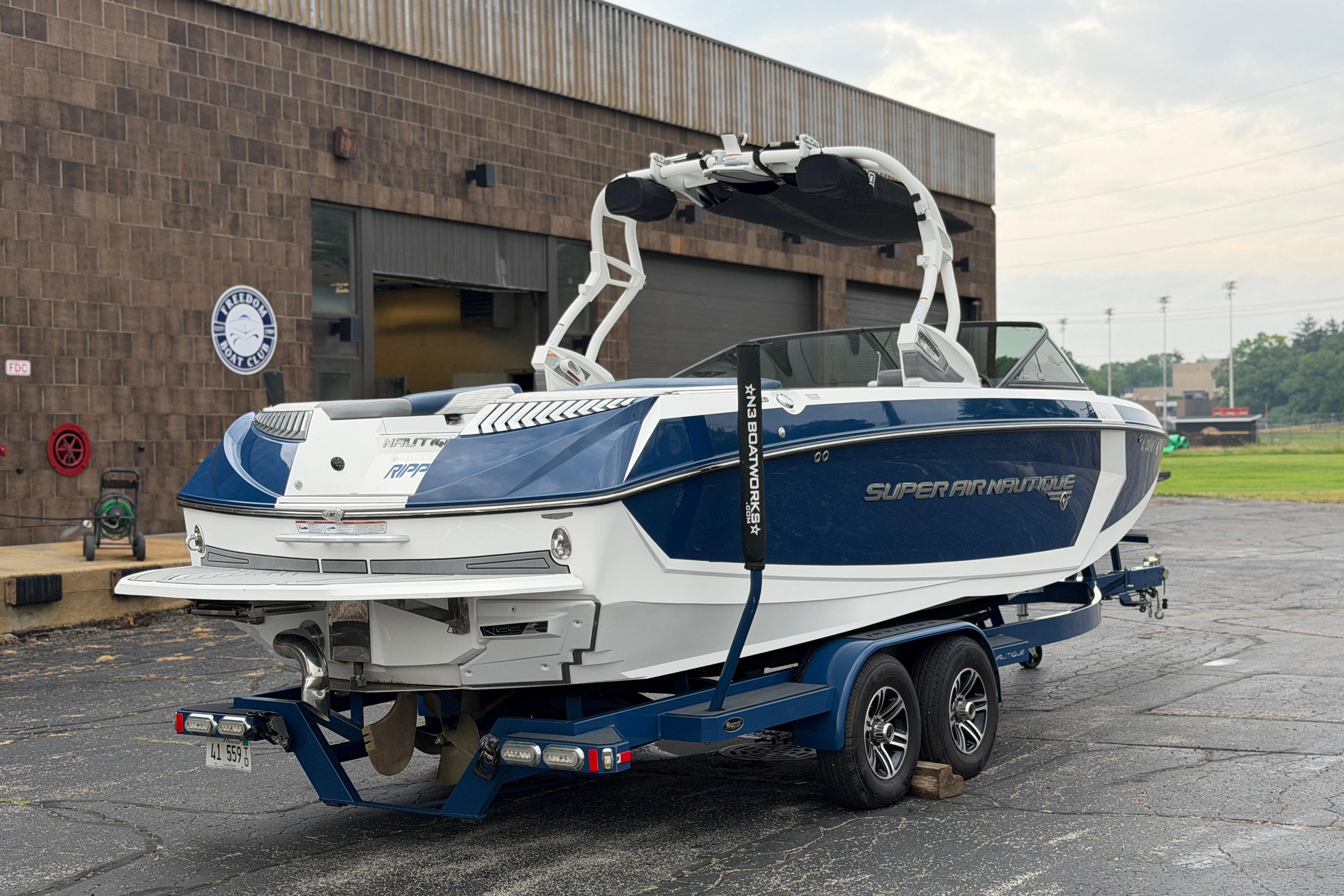 2016 Naitique G25 boat on trailer, parked outside a building.
