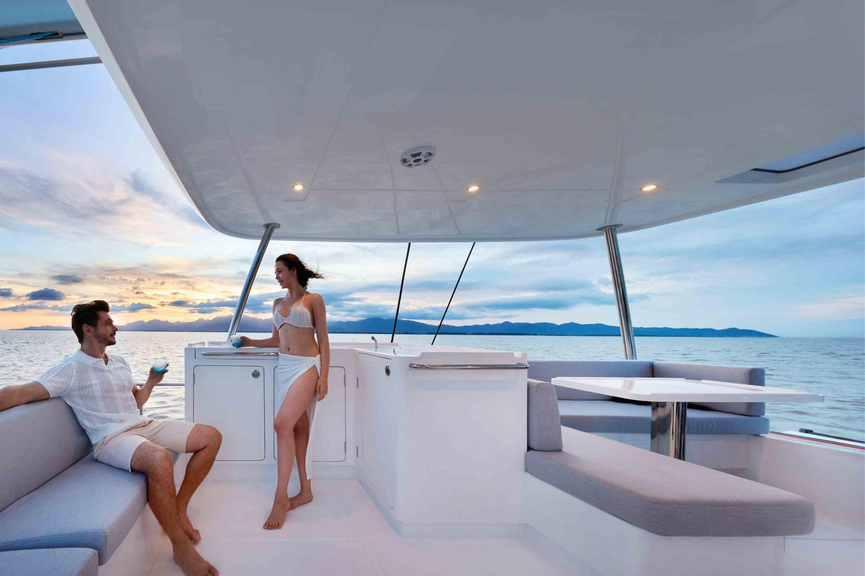 Couple relaxing on Heysea SV50 yacht, 2026 model, enjoying ocean views at sunset.