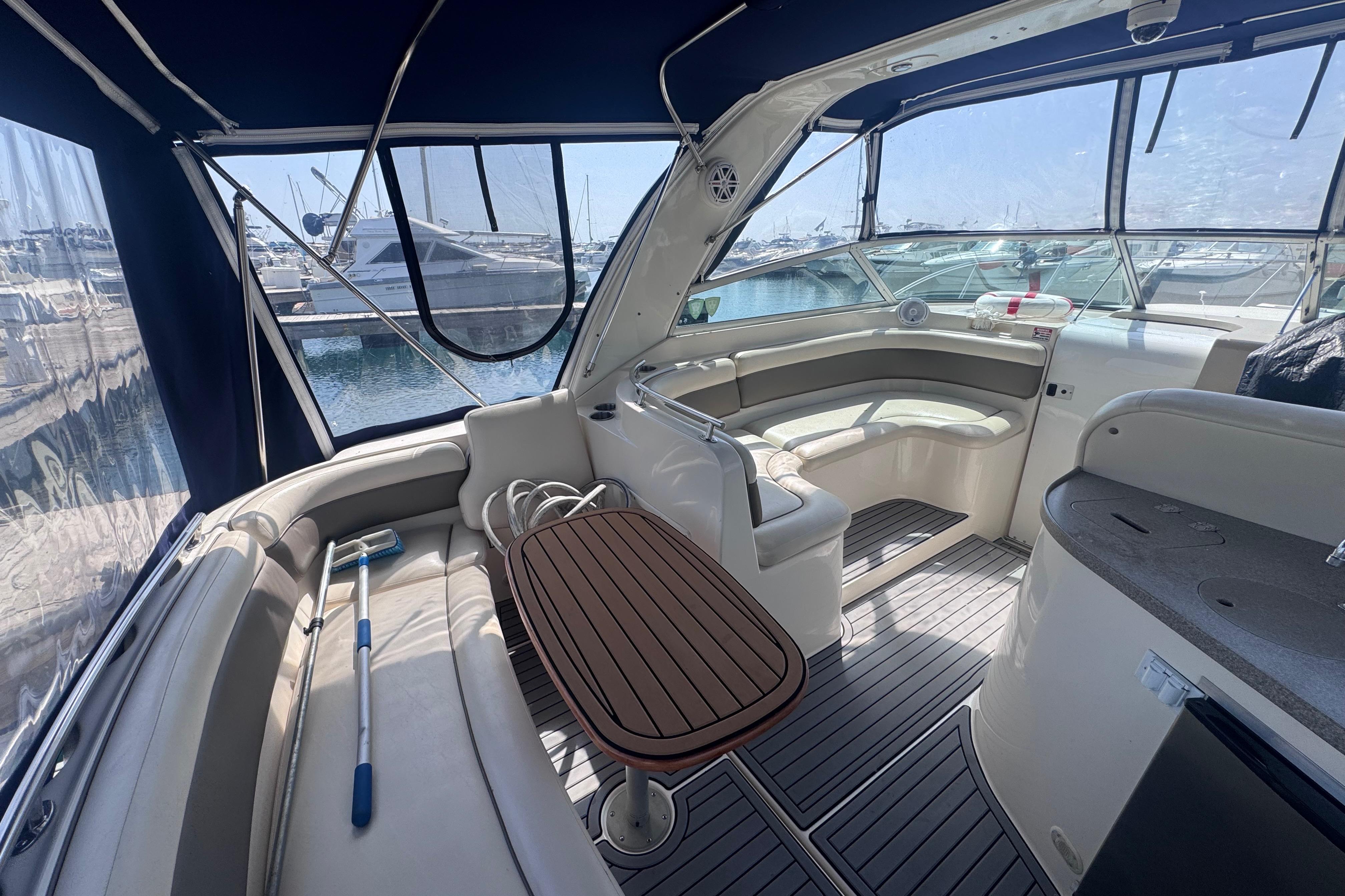 Interior of a 2003 Rinker Fiesta Vee 312 yacht with seating and table, docked at marina.