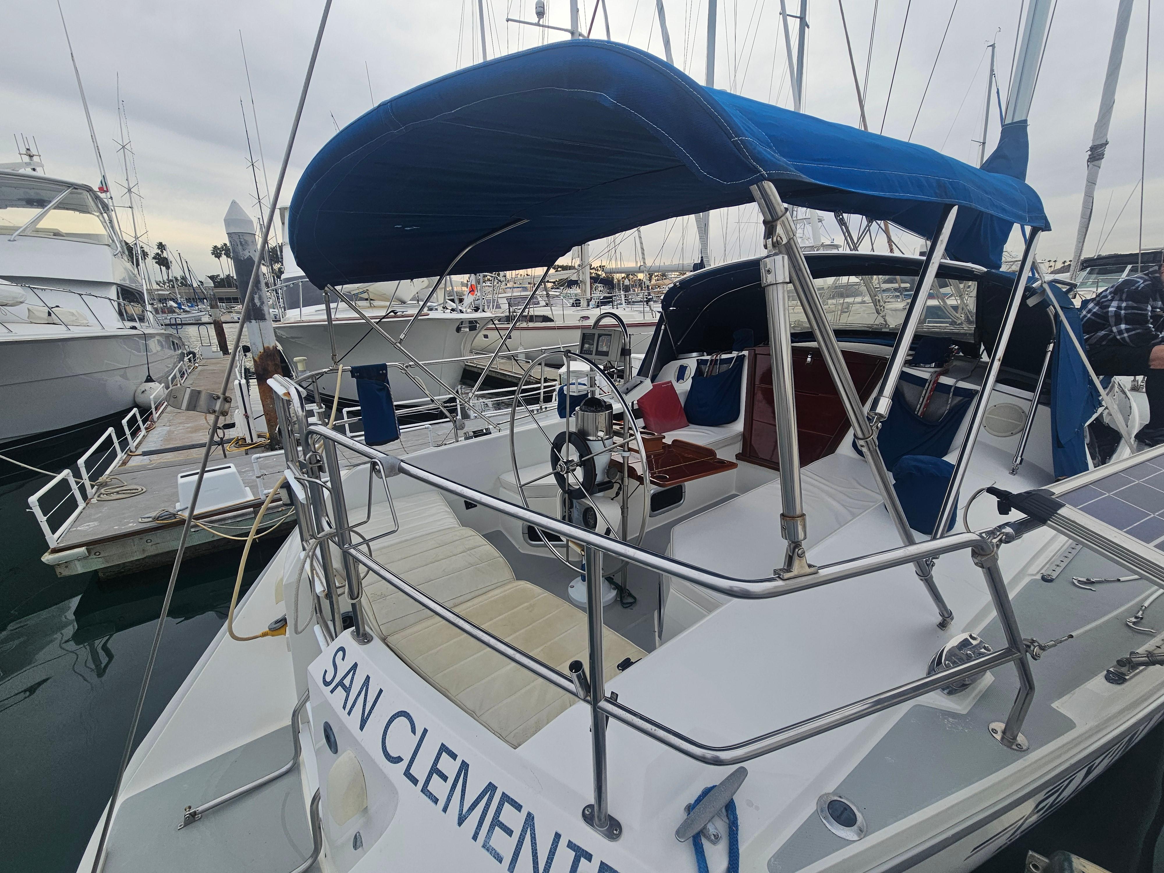 Catalina 42 sailboat, 1990 model, docked with blue canopy and visible steering wheel.