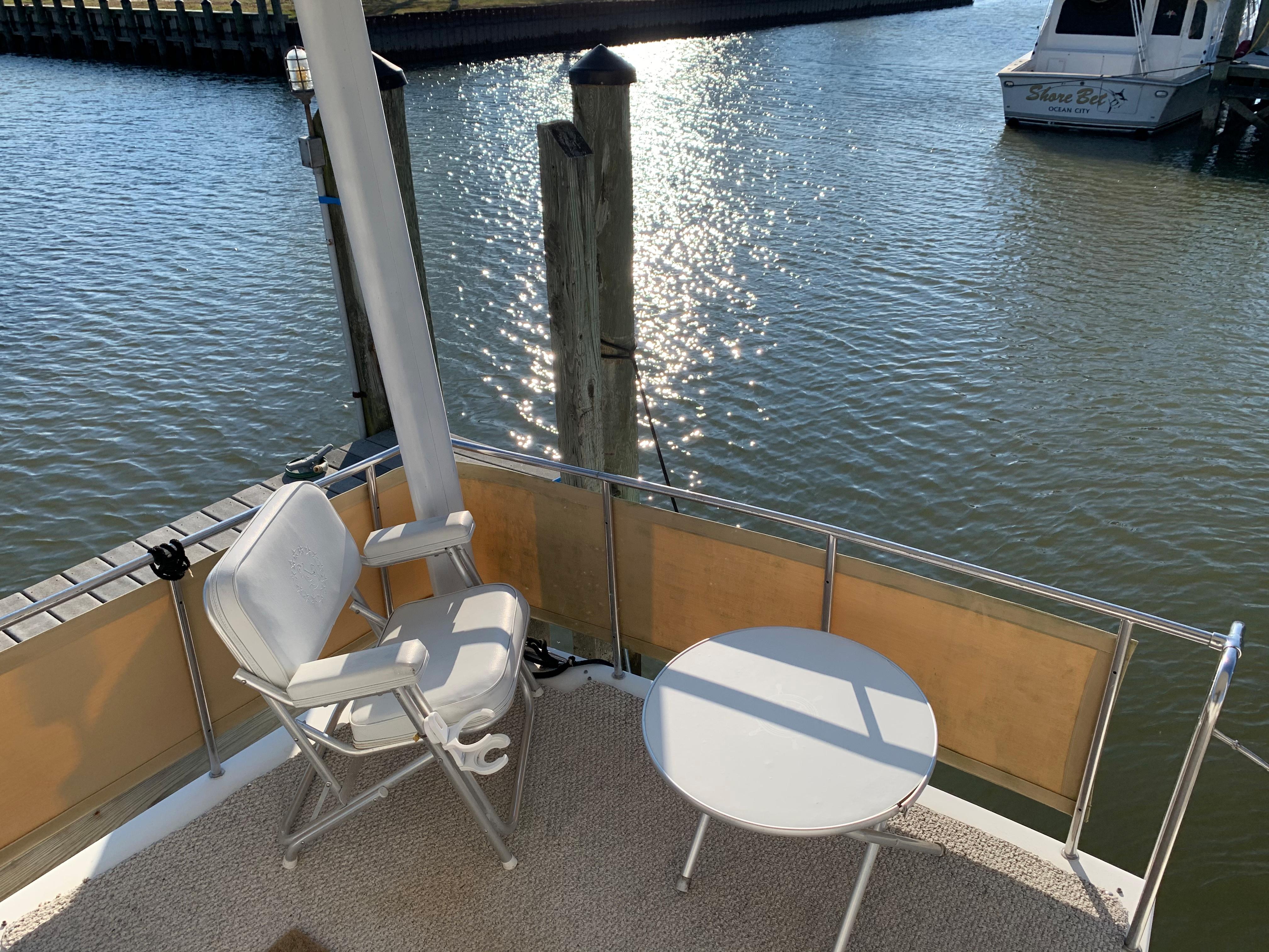 1992 Silverton 34 Aft Cabin Motor Yacht deck with chairs and table by the water.