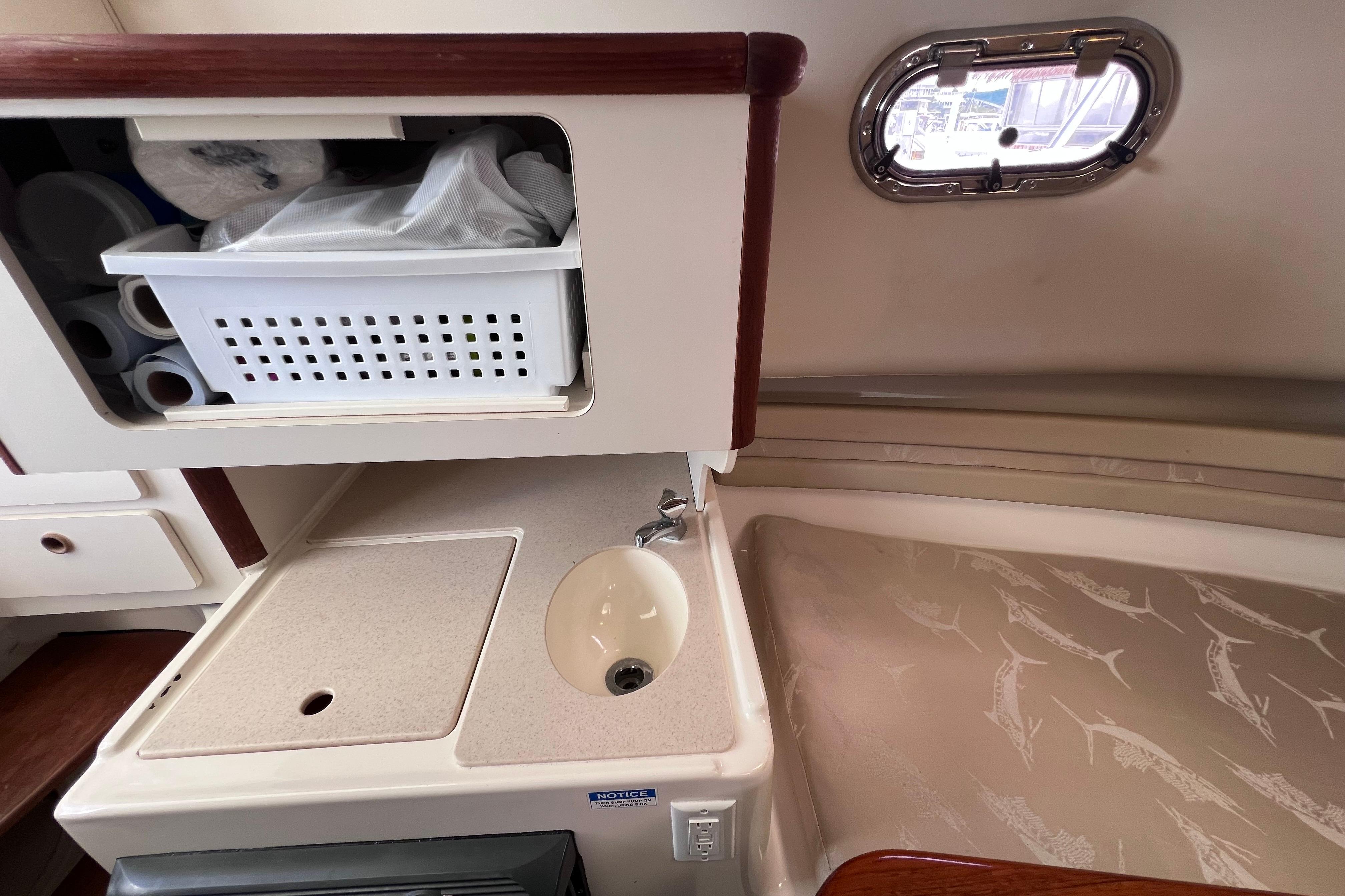 2004 Pursuit 2870 Walkaround cabin interior with sink, storage, and porthole window.