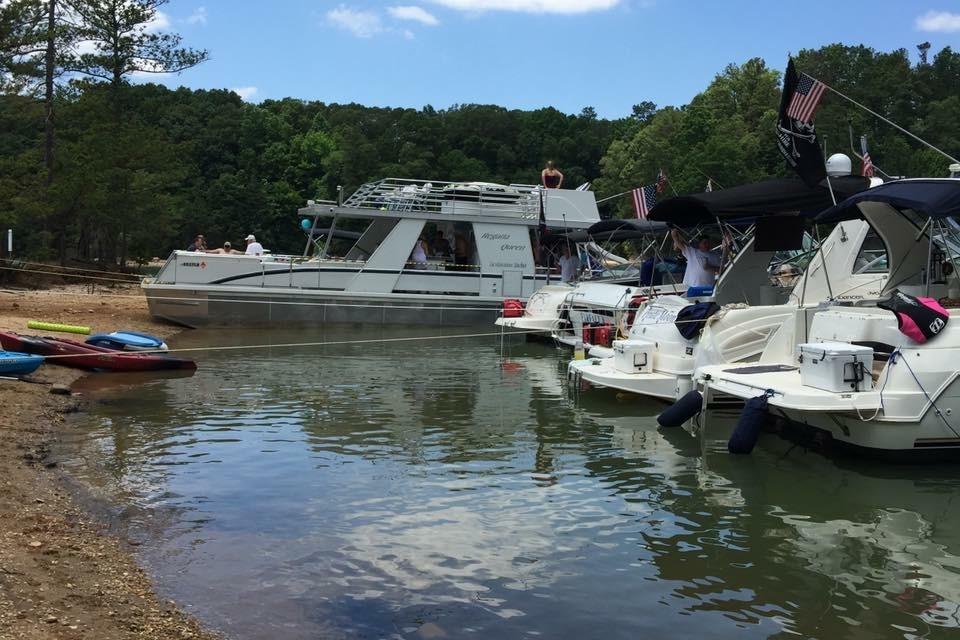 Boats docked by a lakeside, featuring a 2008 Destination Yachts 45X14 houseboat.