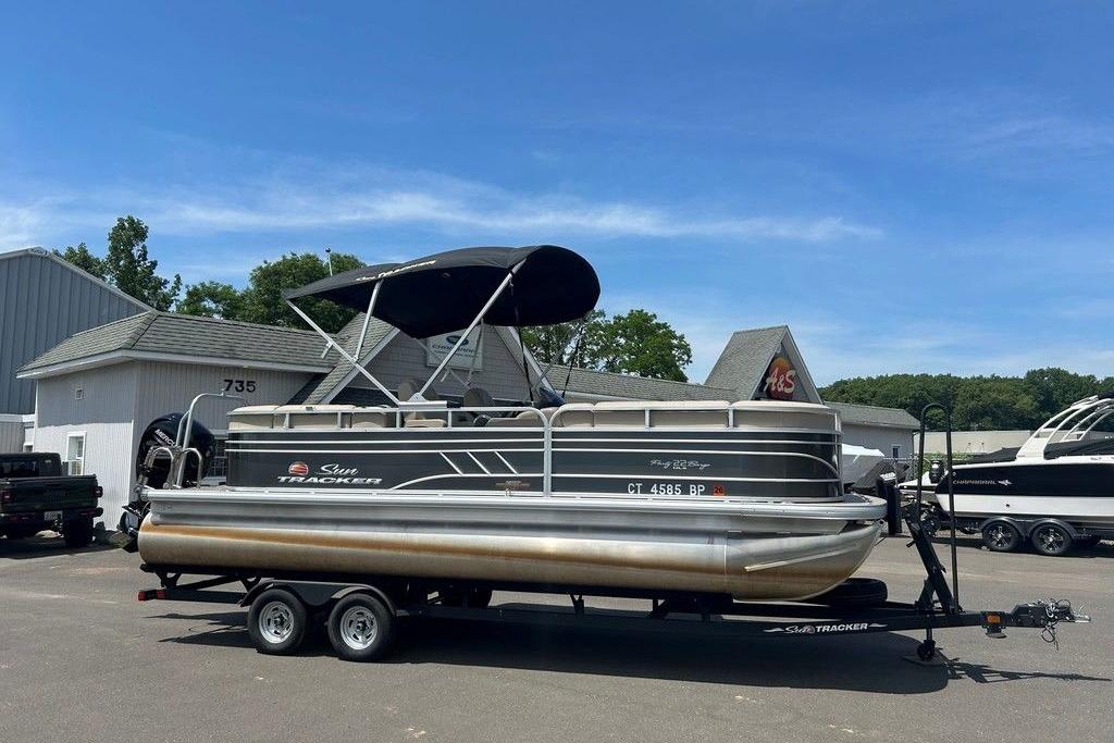 2023 Sun Tracker Party Barge 22 DLX pontoon boat on trailer, parked outdoors.