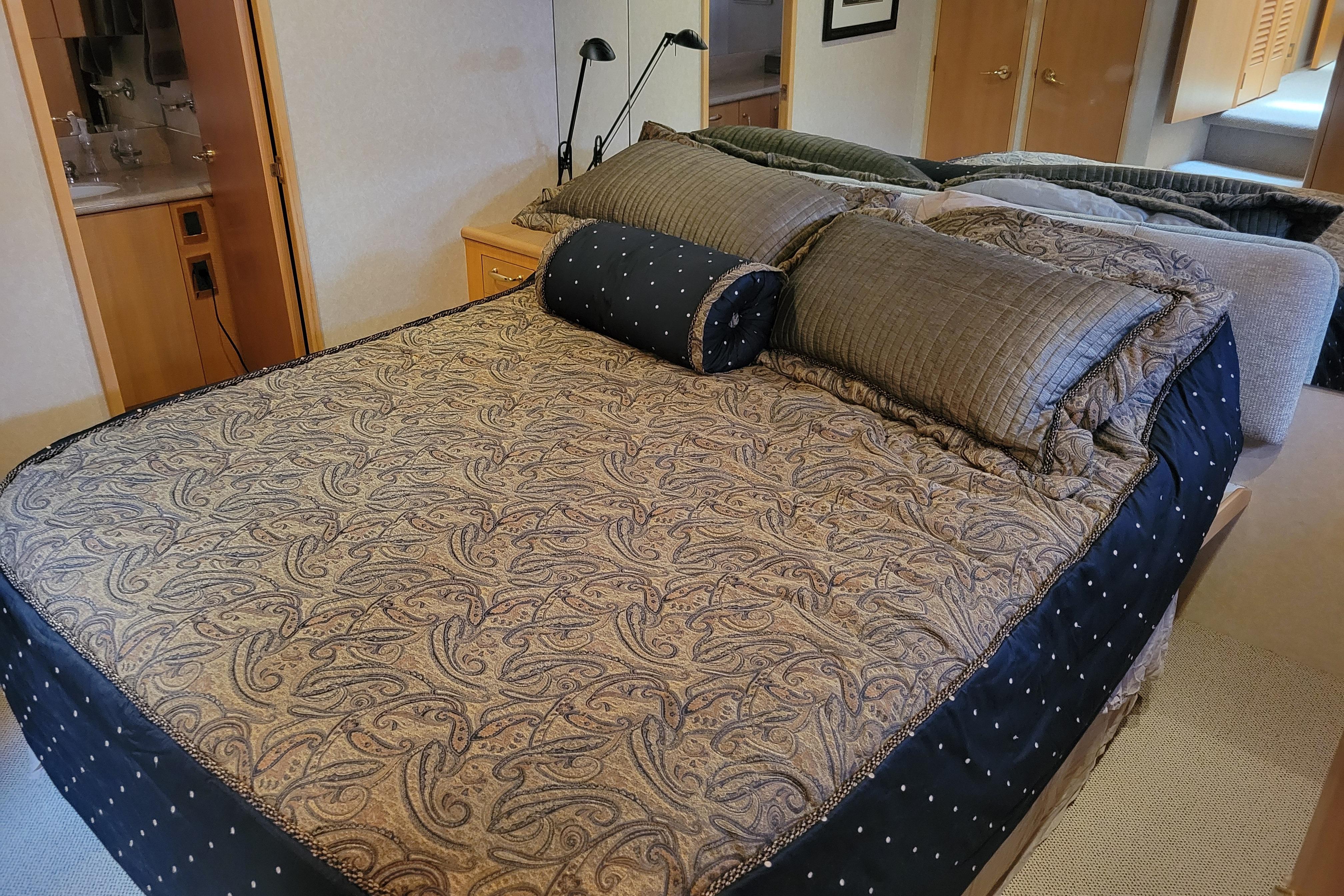 Luxurious bedroom interior of 1998 Tollycraft 65 Pilothouse yacht with elegant bedding.