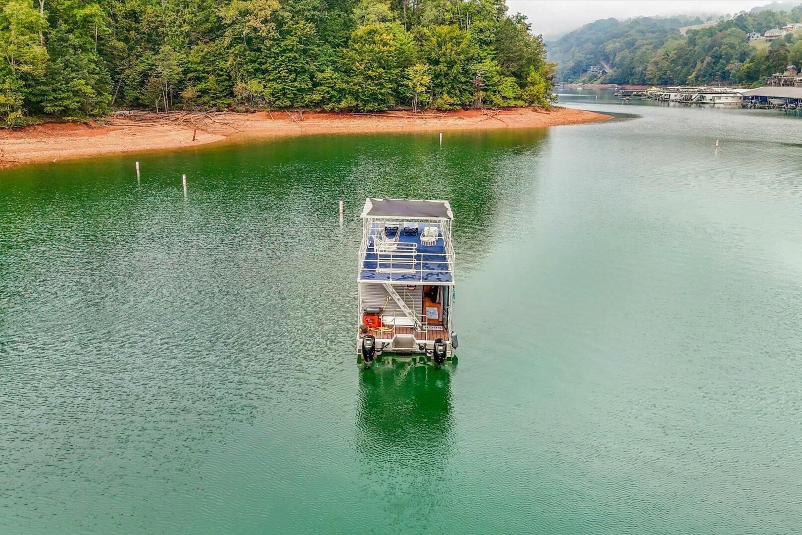 Houseboat on serene lake surrounded by lush trees, Gospel 39 model, 2024.