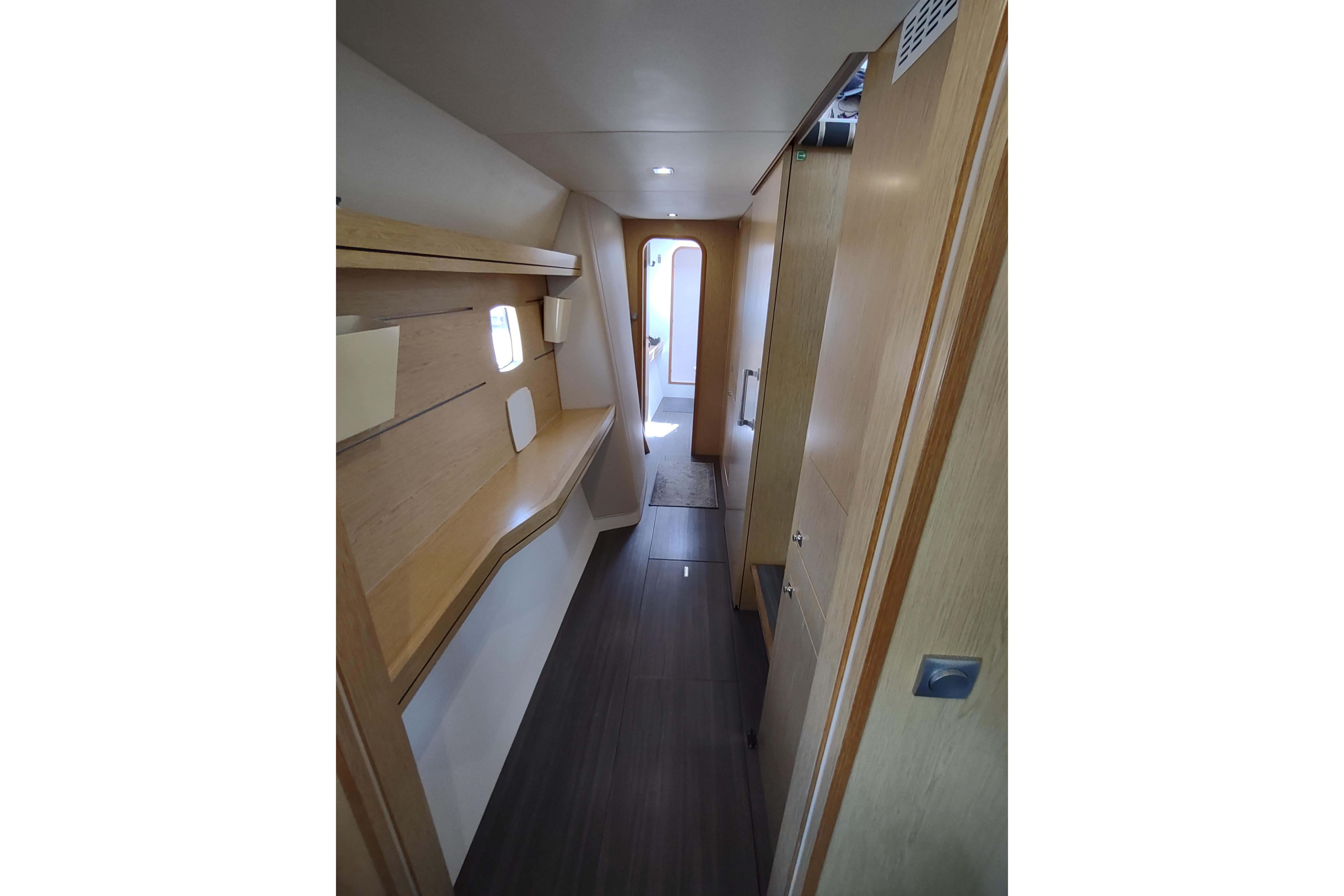 Interior hallway of 2020 Outremer 51 yacht, featuring sleek wooden design and modern lighting.