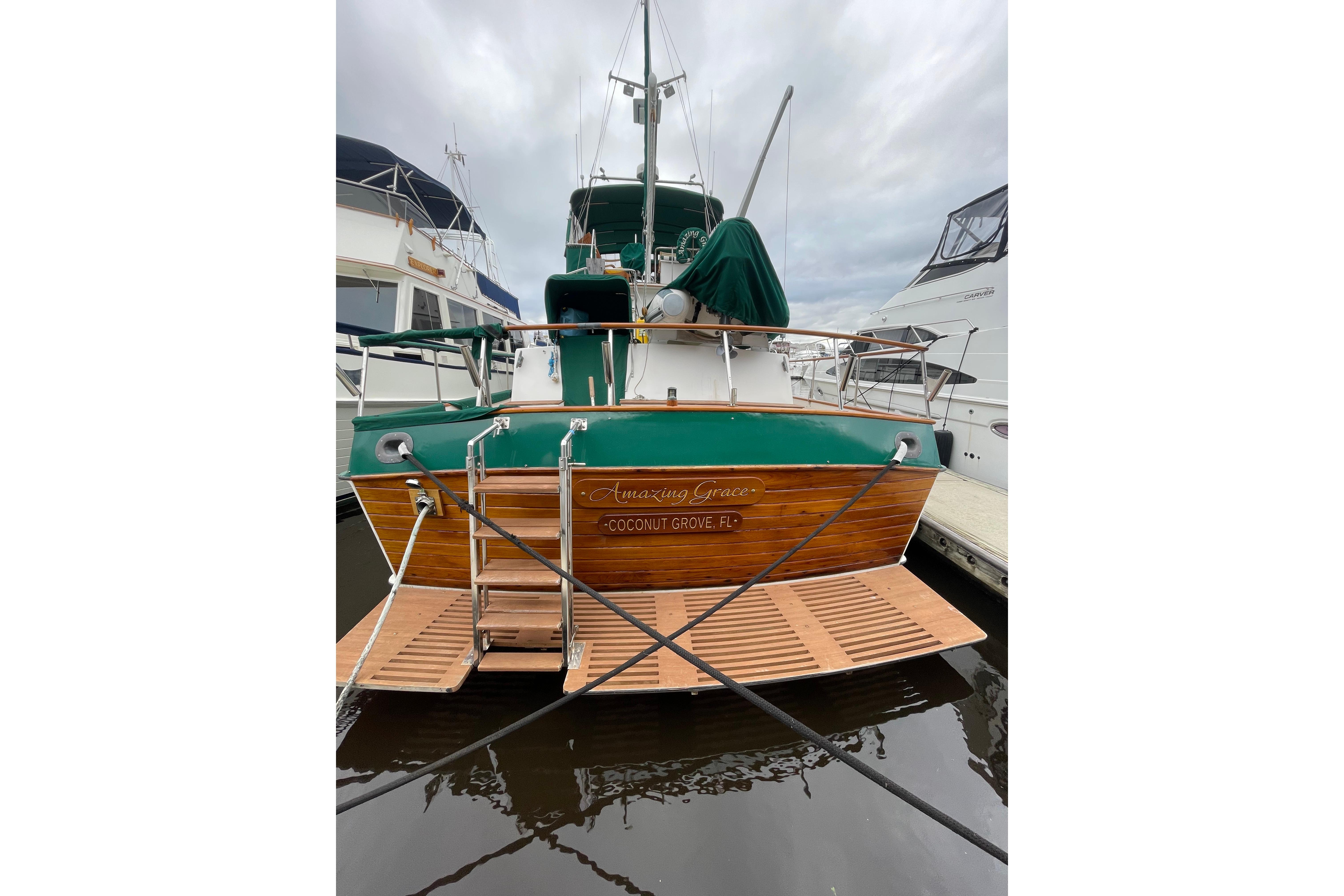 1983 Grand Banks 49 Classic yacht docked, rear view with wooden deck and green accents.