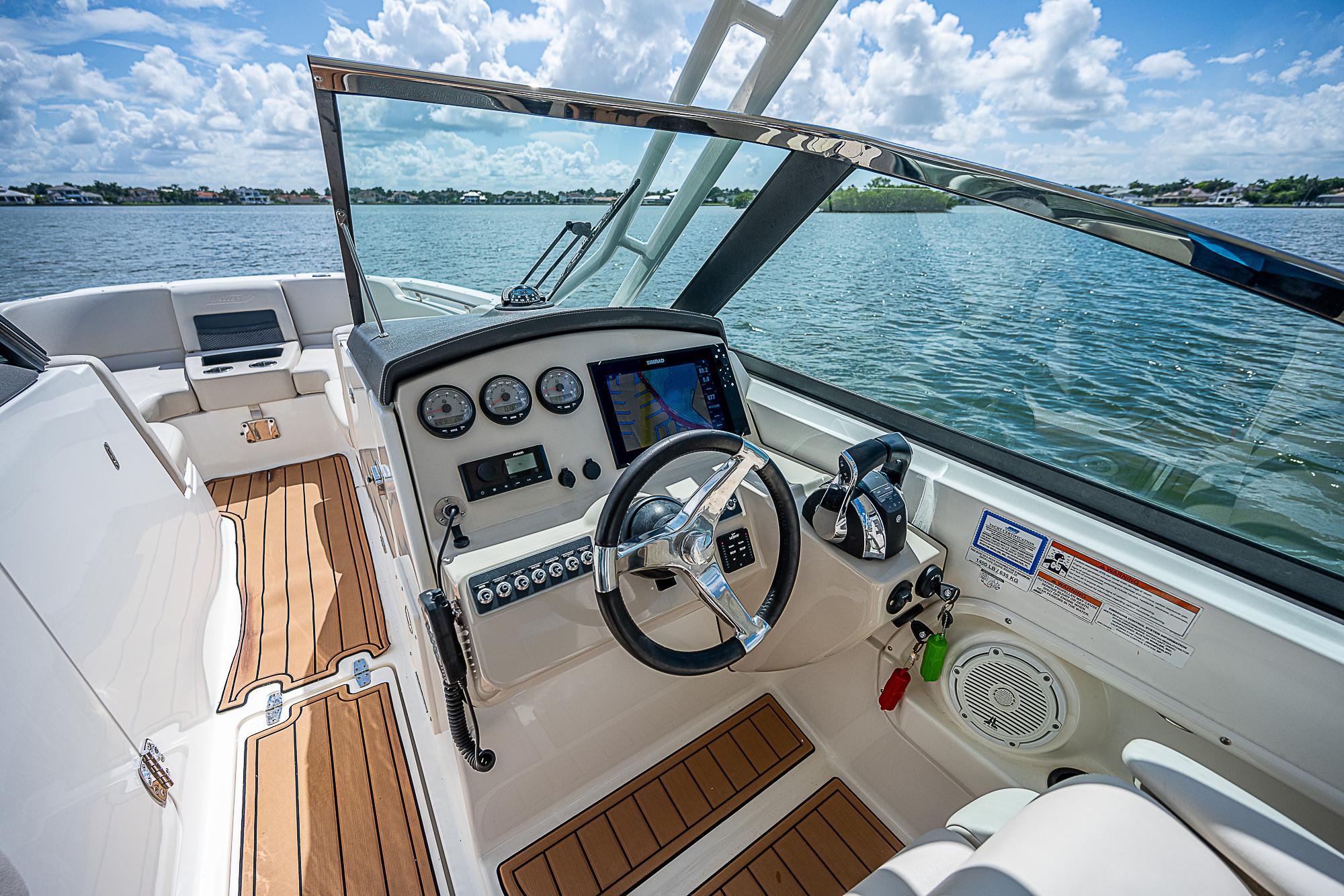 2018 Boston Whaler 270 Vantage boat interior with steering wheel and dashboard, on a sunny day.