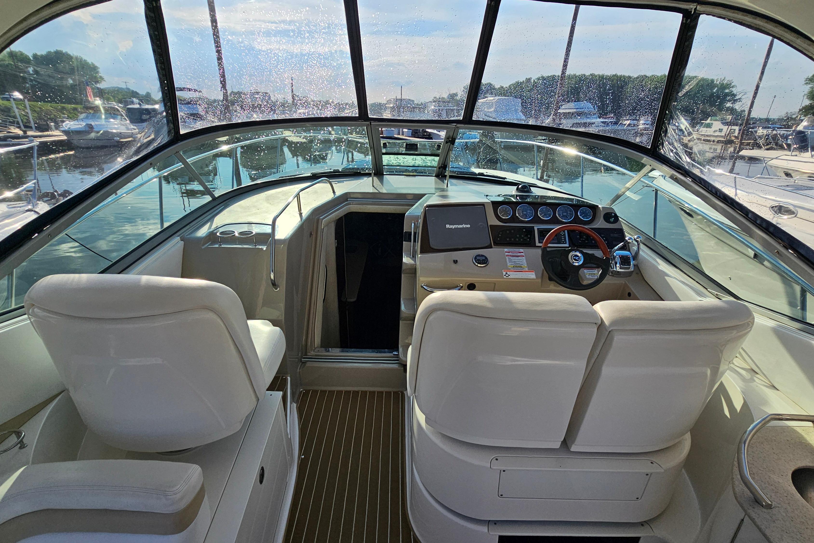 2008 Sea Ray Sundancer 350 cockpit with helm, white seats, and marina view.
