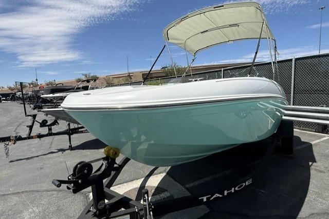 2026 Tahoe T18 boat on trailer with canopy, parked outdoors under blue sky.