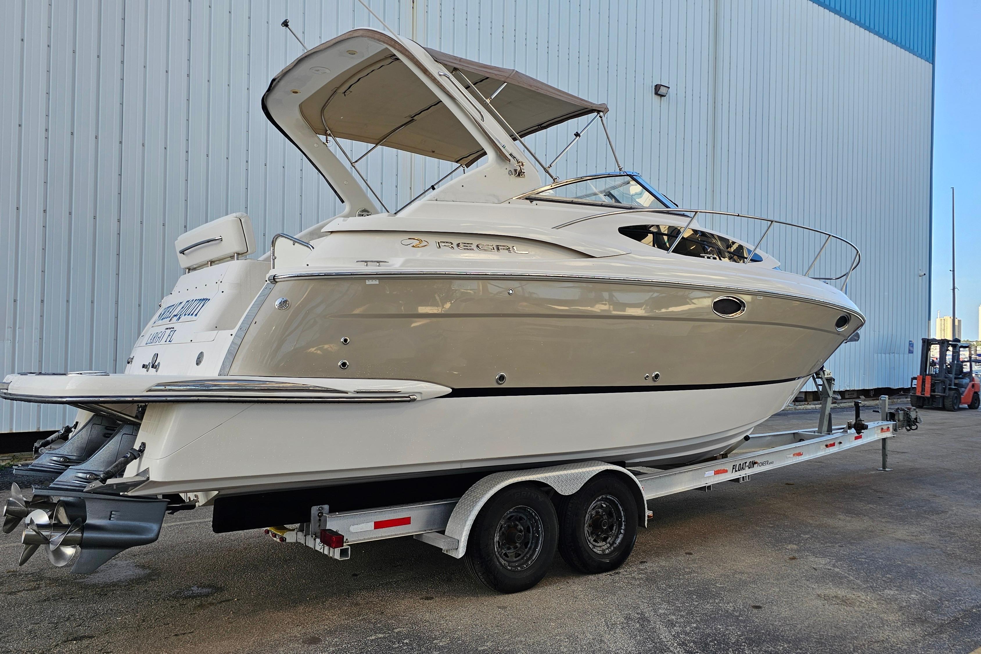 2005 Regal 3060 Window Express boat on trailer, parked near a large building.