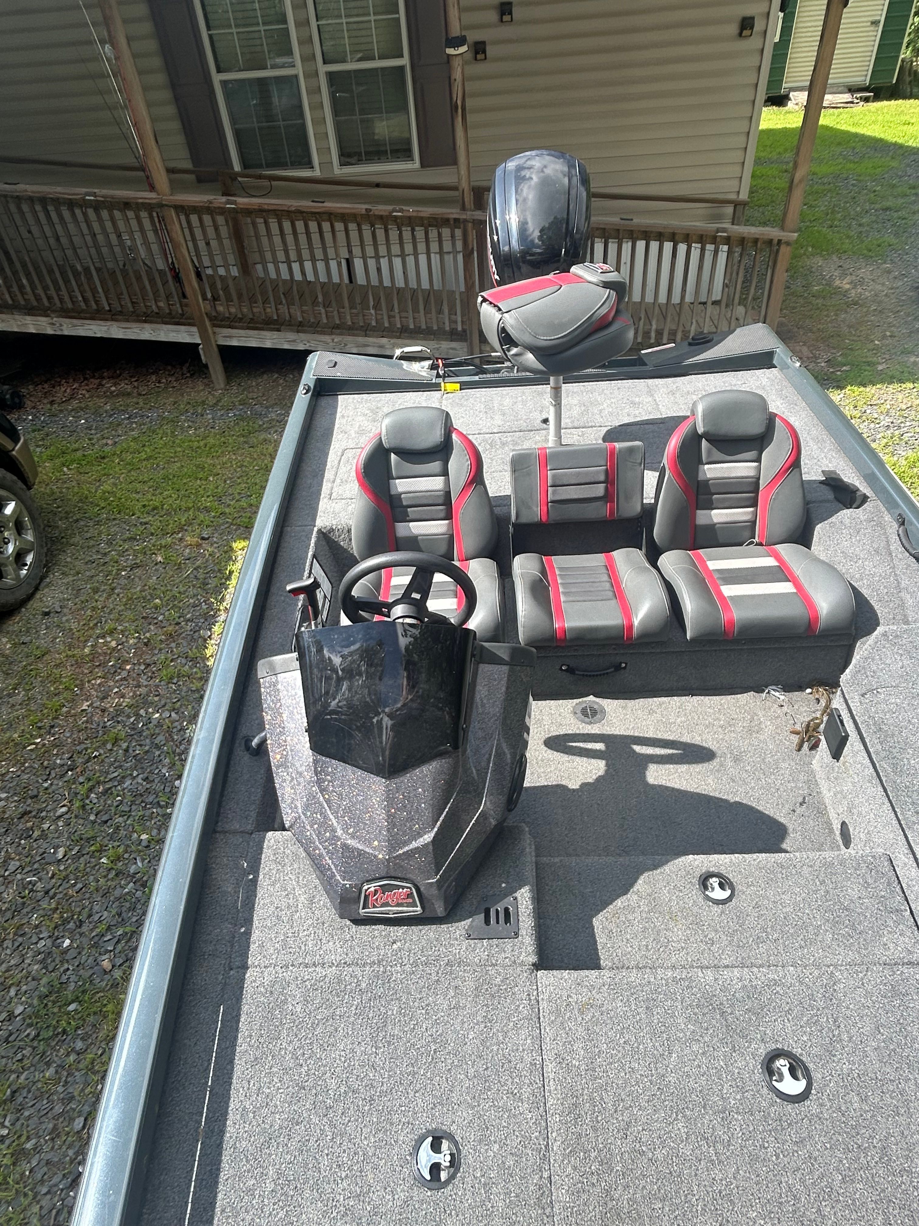 The boat has gray and red seats and a steering wheel, parked on a trailer.