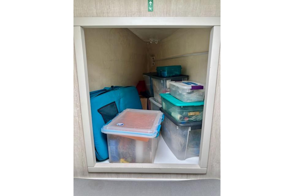 Storage compartment filled with plastic bins and bags in a 2017 Leopard 40.