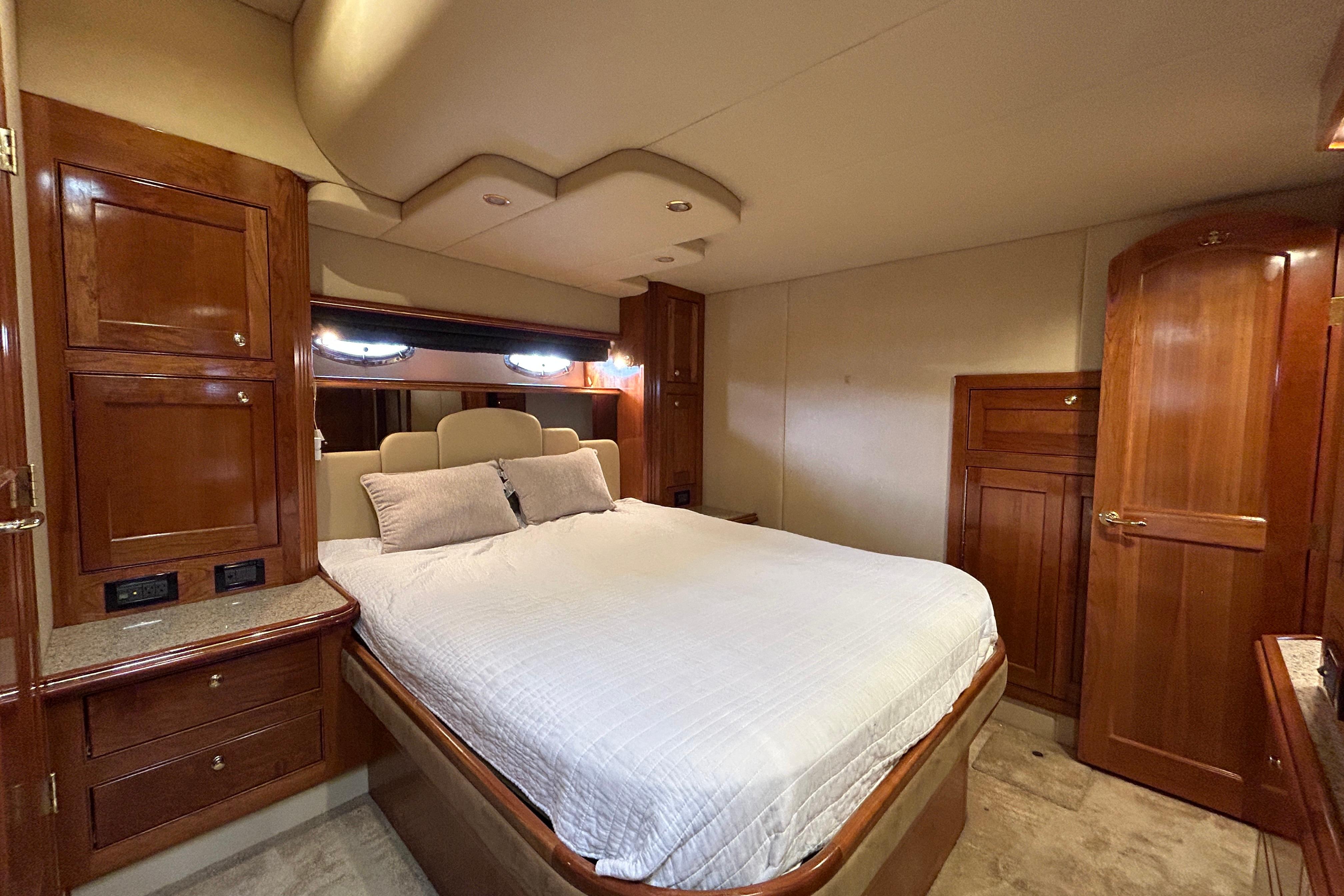 Luxurious bedroom interior of 2003 Cruisers Yachts 540 Express with wood cabinetry and plush bedding.