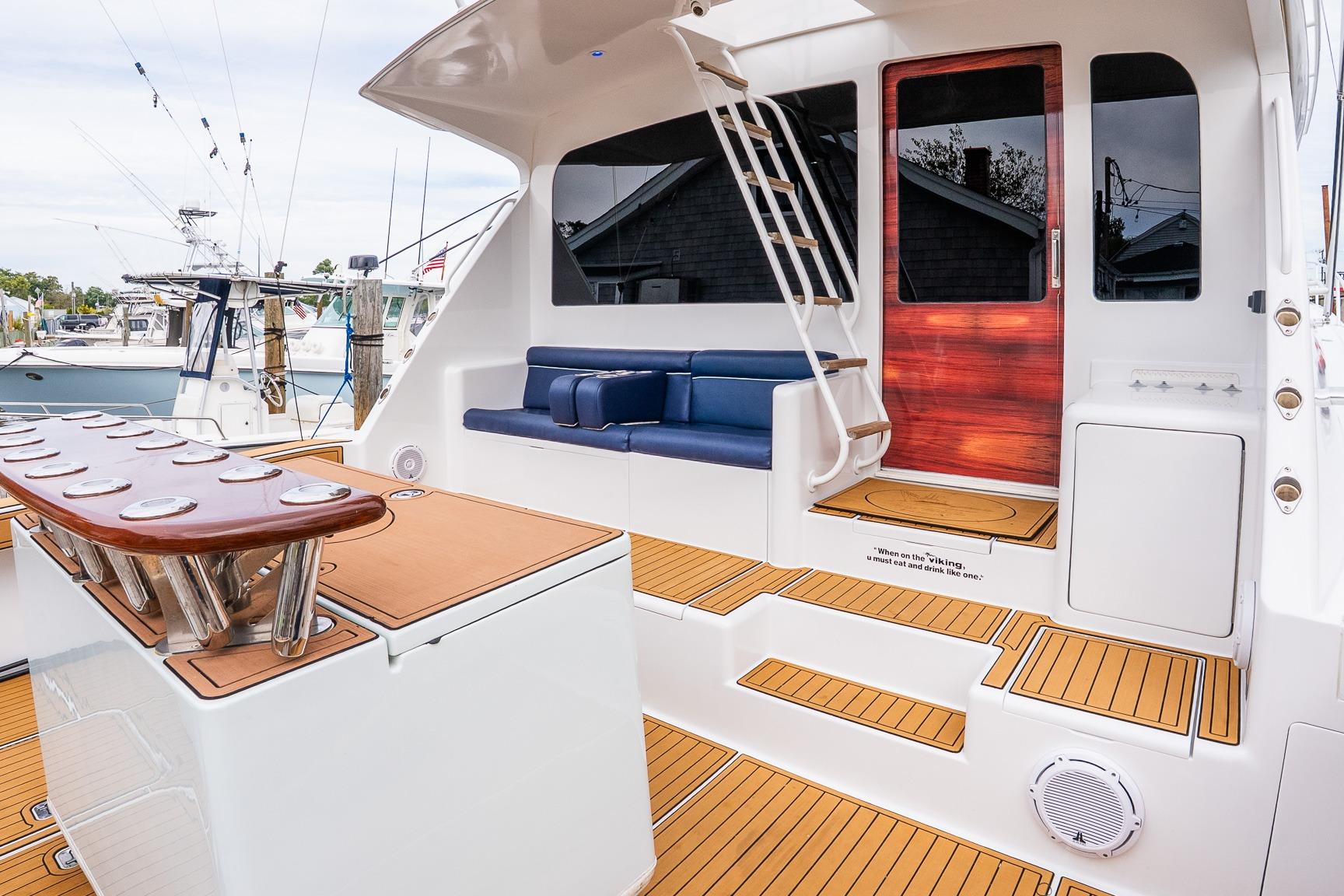 2002 Viking 61 Enclosed Bridge yacht with teak deck, blue seating, and fishing rod holders.