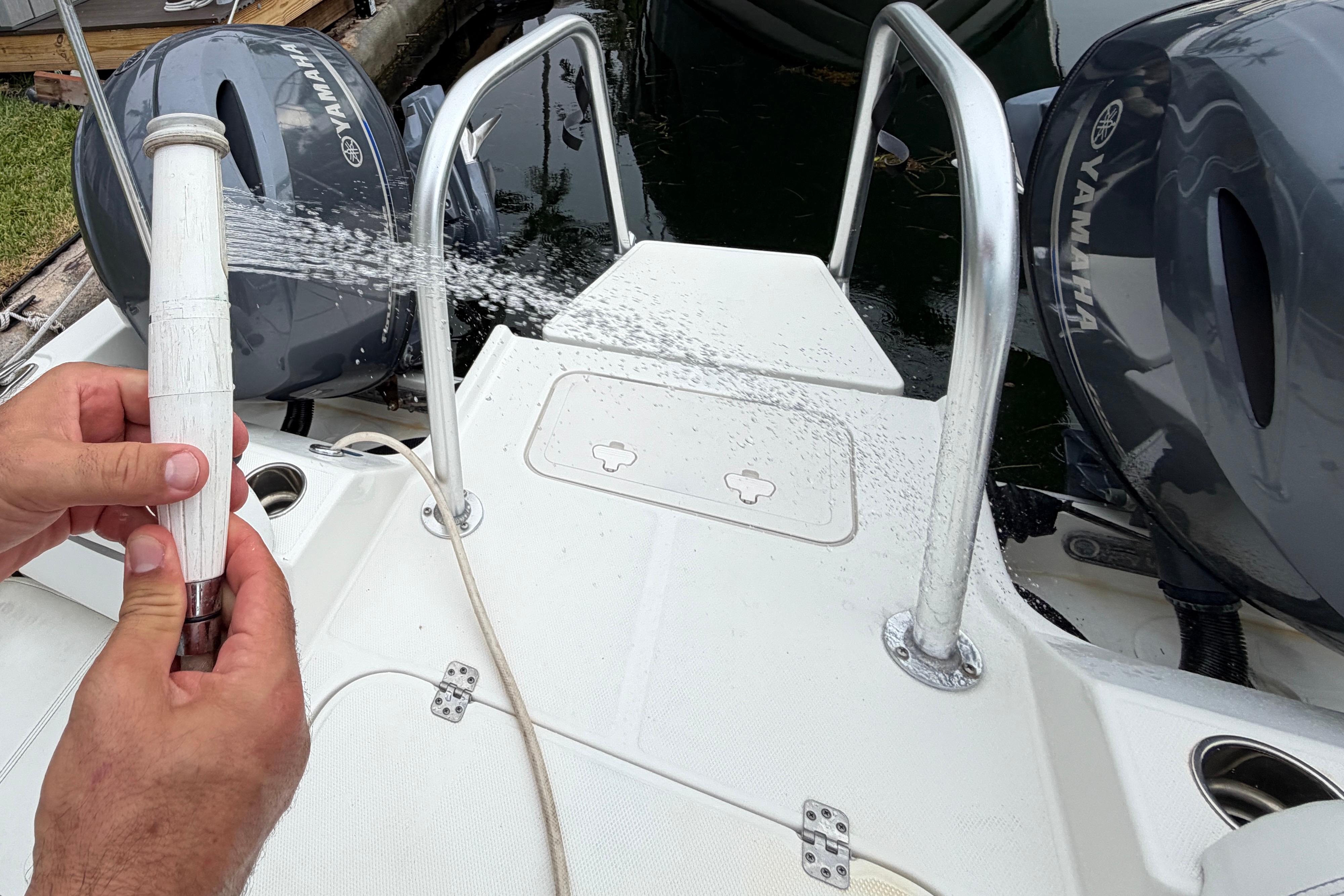 Boat deck of 2019 World Cat 230 DC with water hose and Yamaha engines.