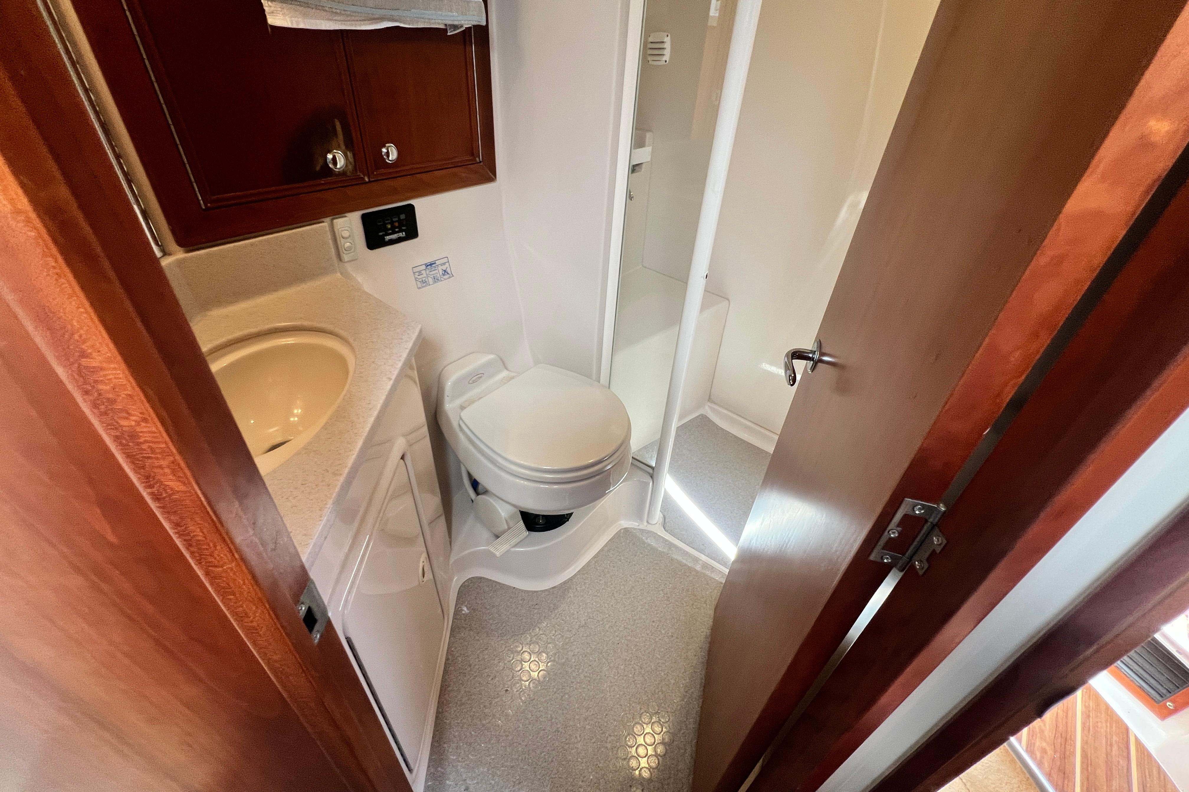 Compact bathroom in 2007 Riviera 33 Flybridge yacht with sink, toilet, and shower.