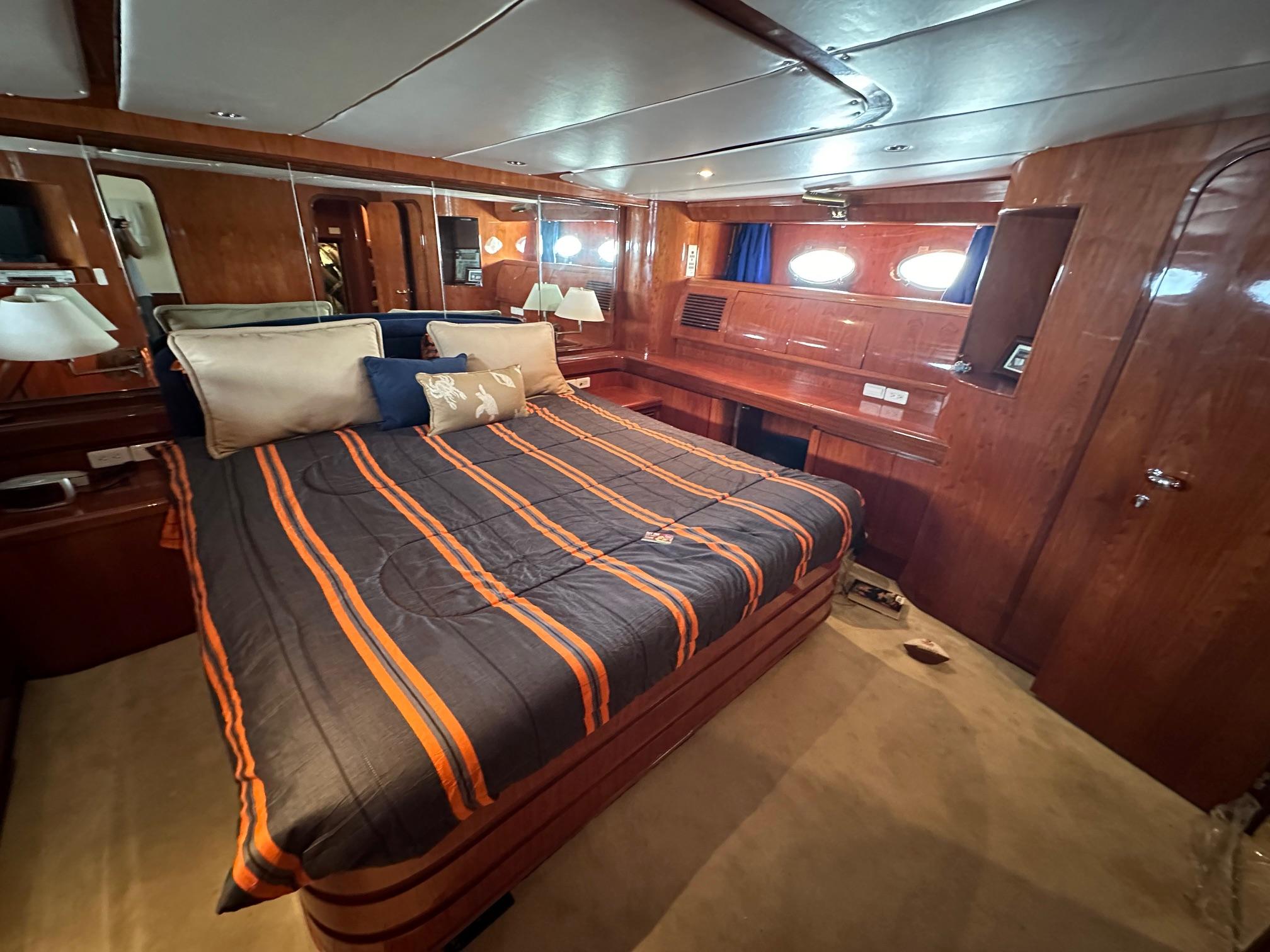 Luxurious cabin interior of 2001 Johnson 70 yacht with striped bedding and wood paneling.