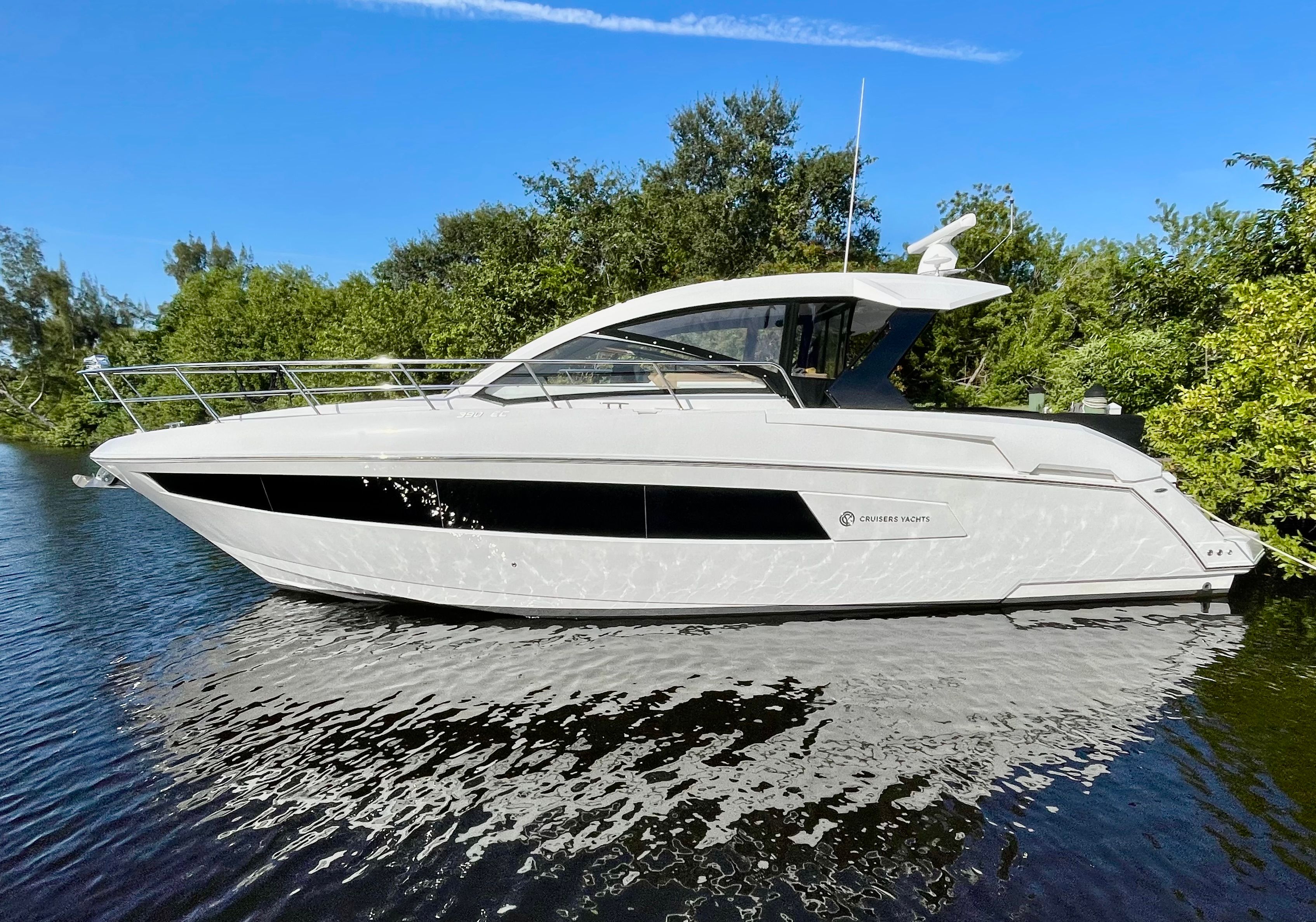 A 2016 Cruisers Yachts 390 Express Coupe on calm water, surrounded by trees.