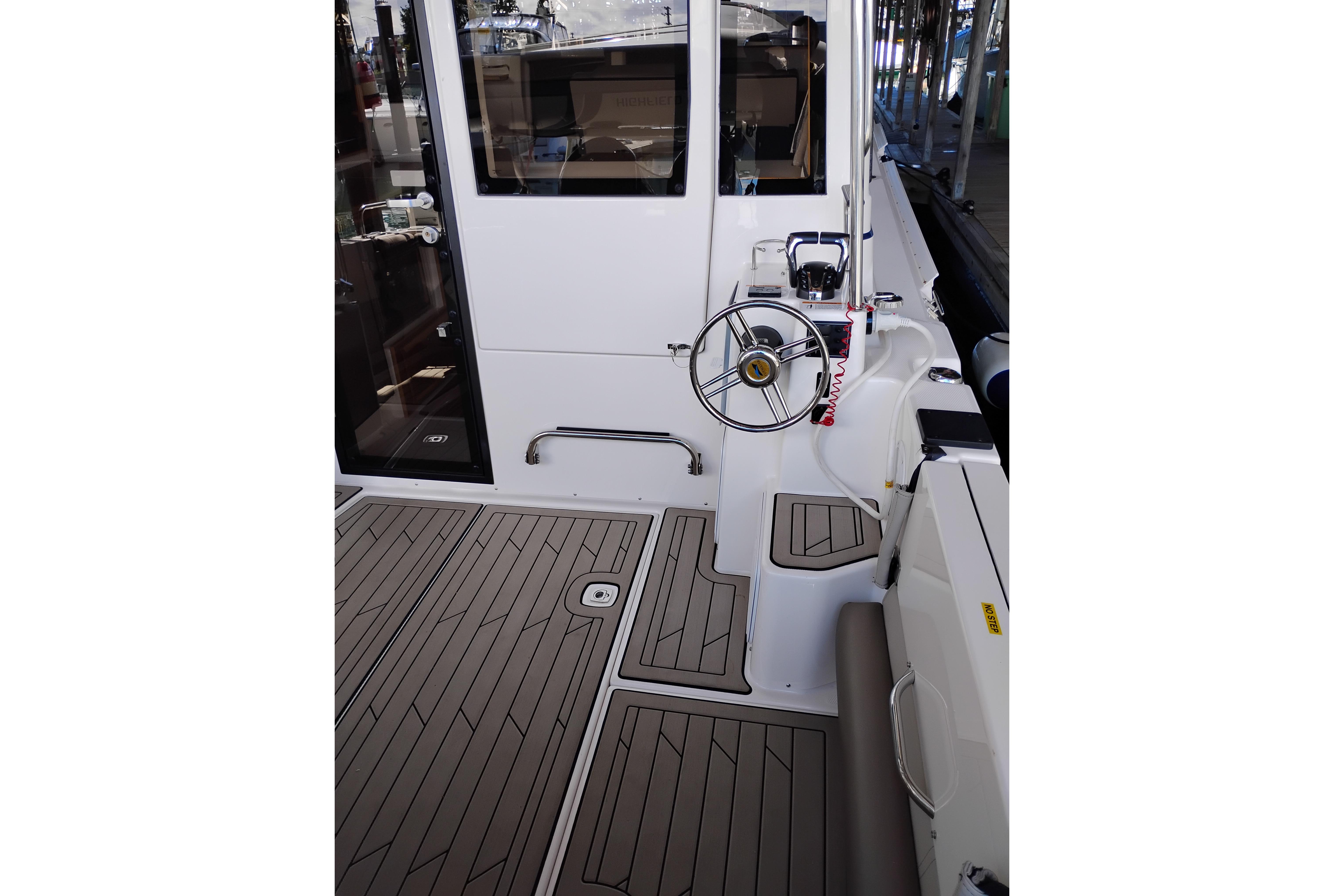2022 Cutwater C-32 Coupe boat cockpit with steering wheel and teak flooring.
