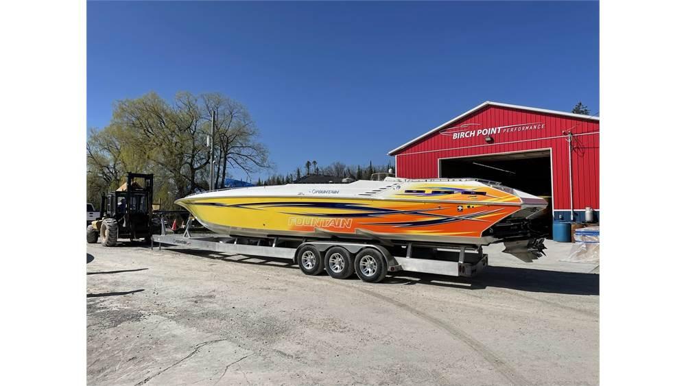 2006 Fountain 42 speedboat on trailer near red building, sunny day.