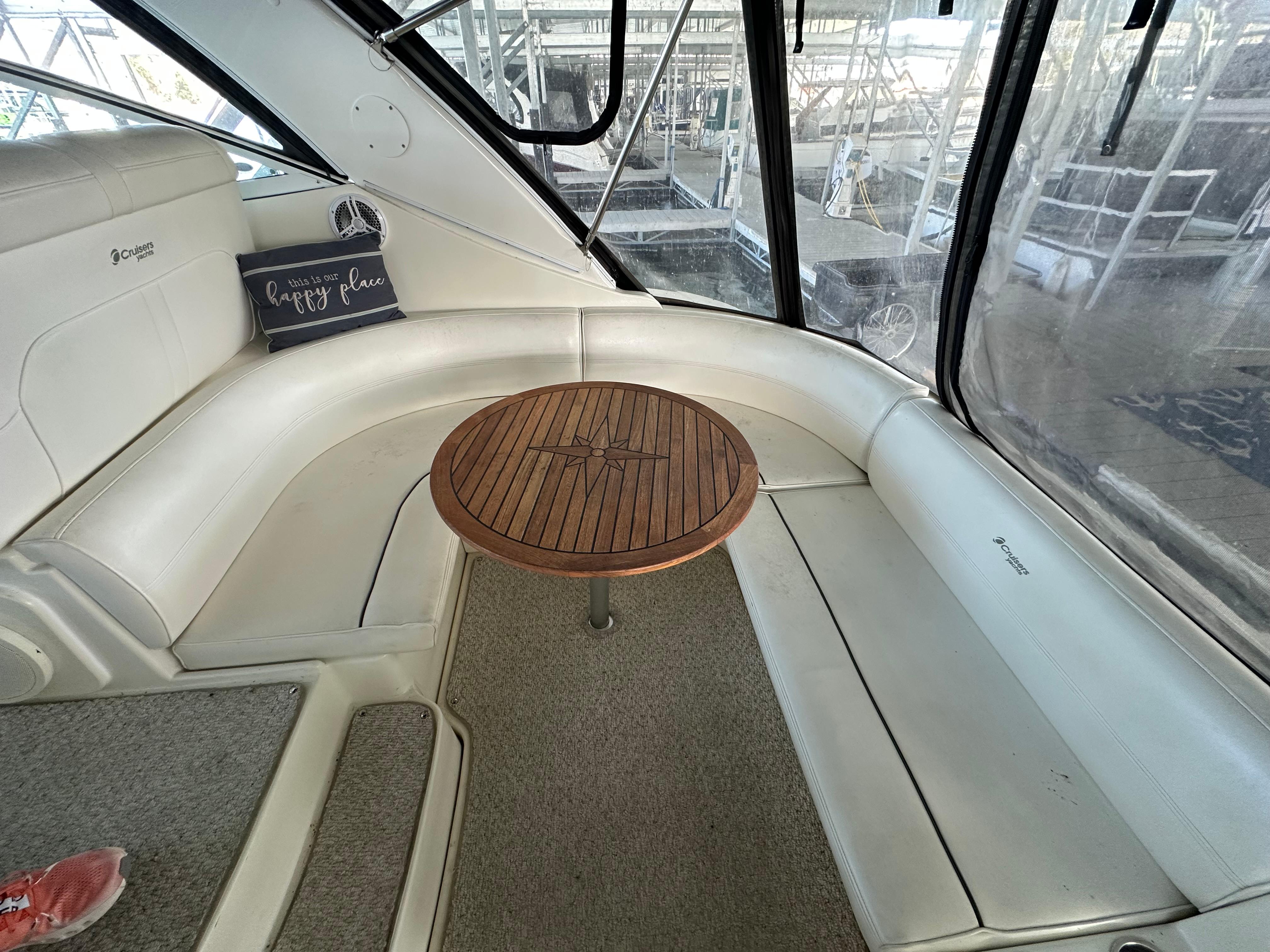 2005 Cruisers Yachts 340 Express interior with curved seating and wooden table.