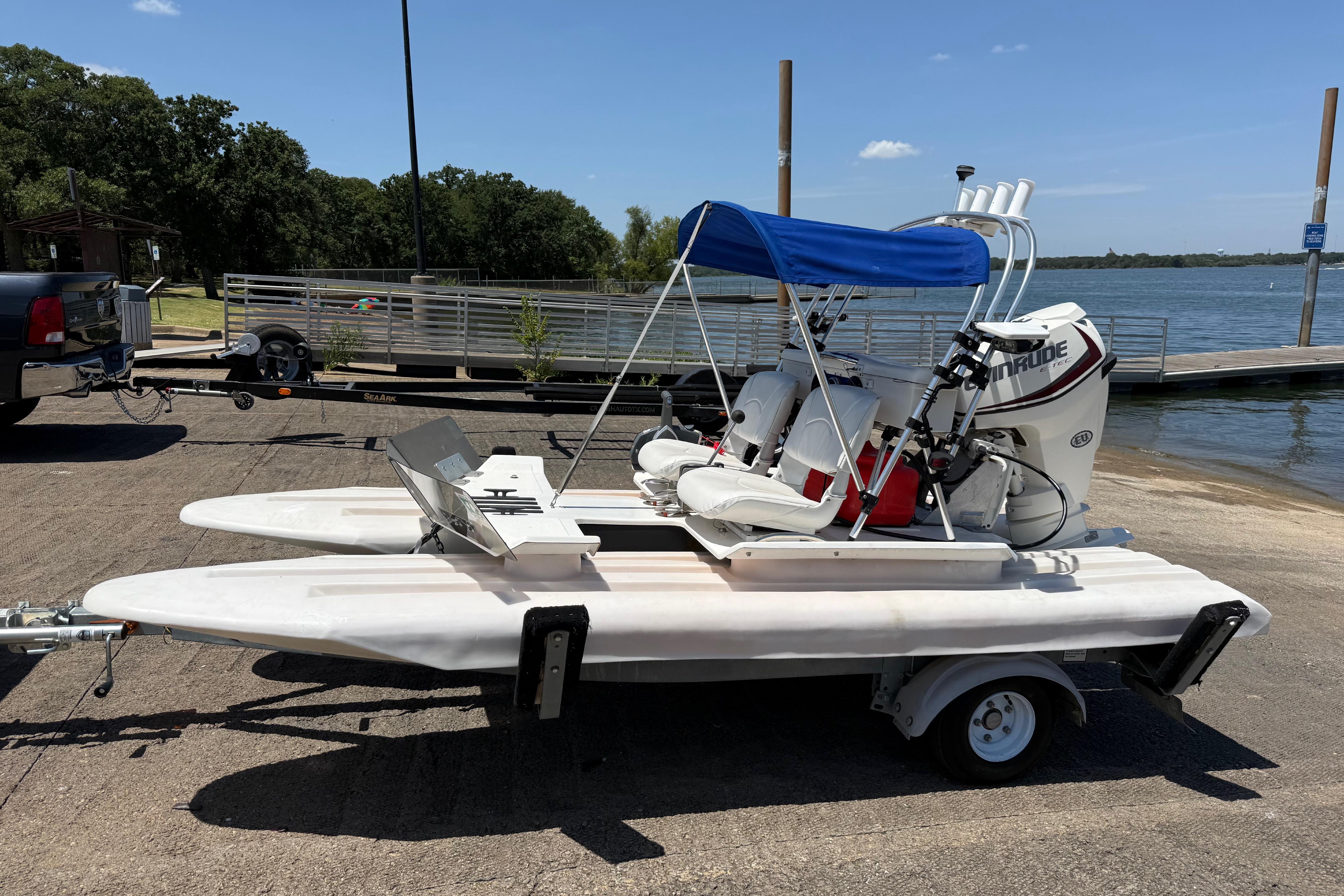 2016 CraigCat E2 Elite on trailer by lakeside dock, featuring blue canopy and Evinrude motor.