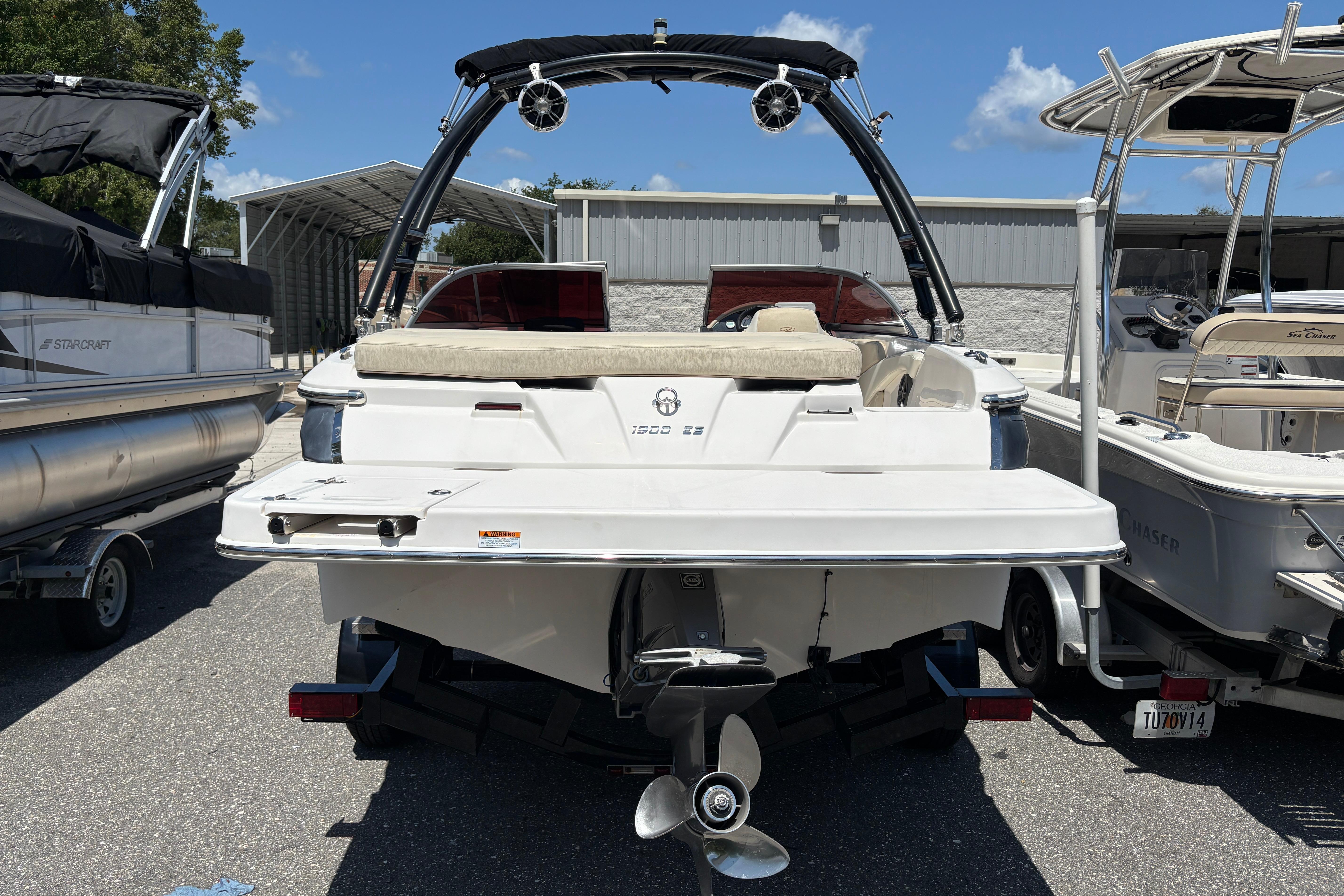 2018 Regal 1900 ES Bowrider boat, rear view, parked between other boats.