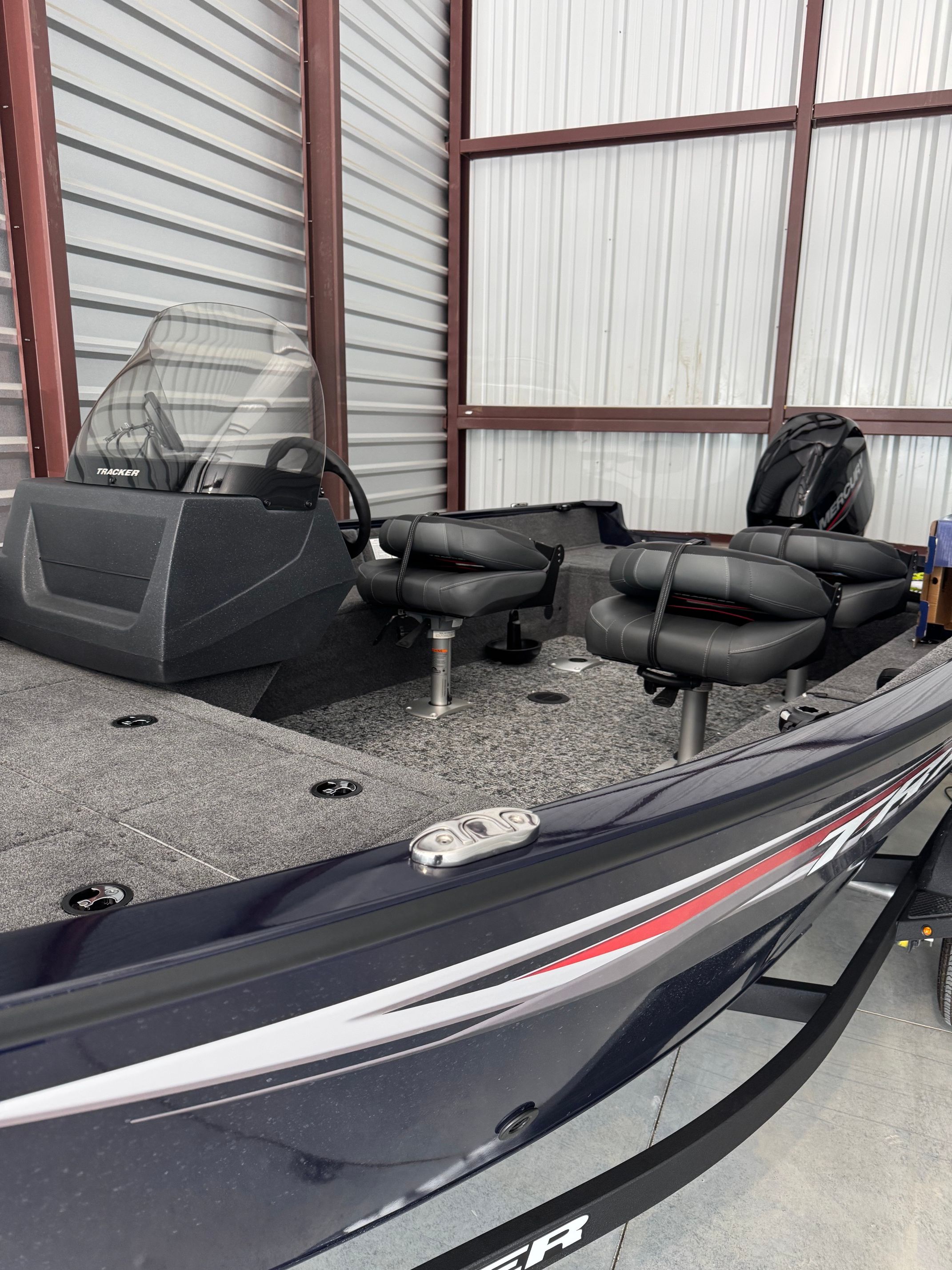 The image shows a 2025 Tracker Pro Guide V-16 SC boat in a warehouse.