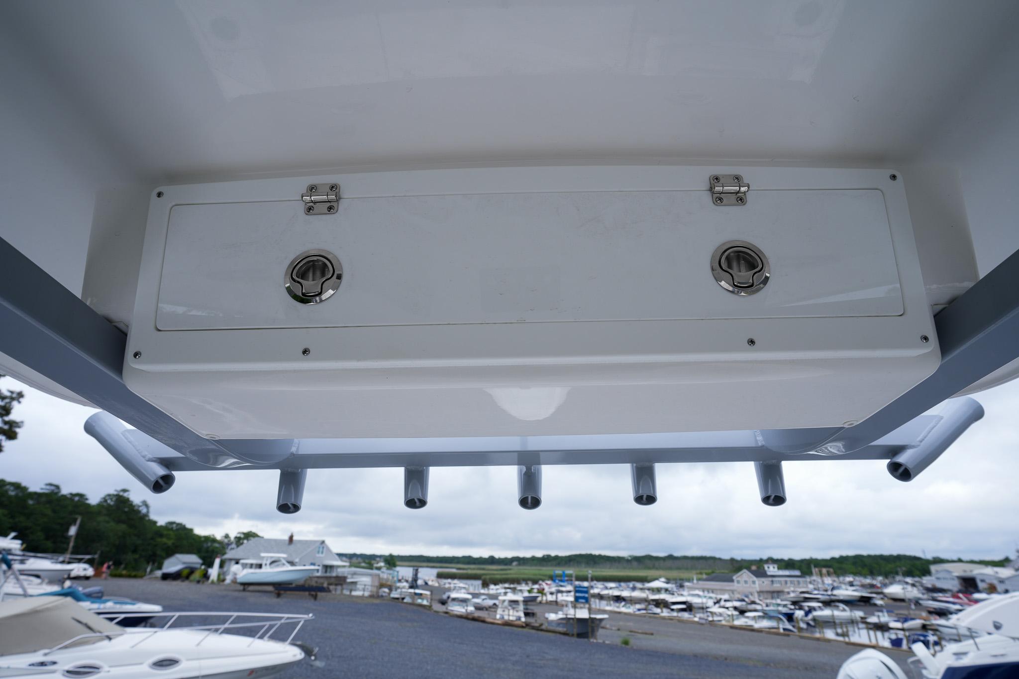 2026 Sea Fox 228 Commander boat storage compartment with rod holders, marina in background.