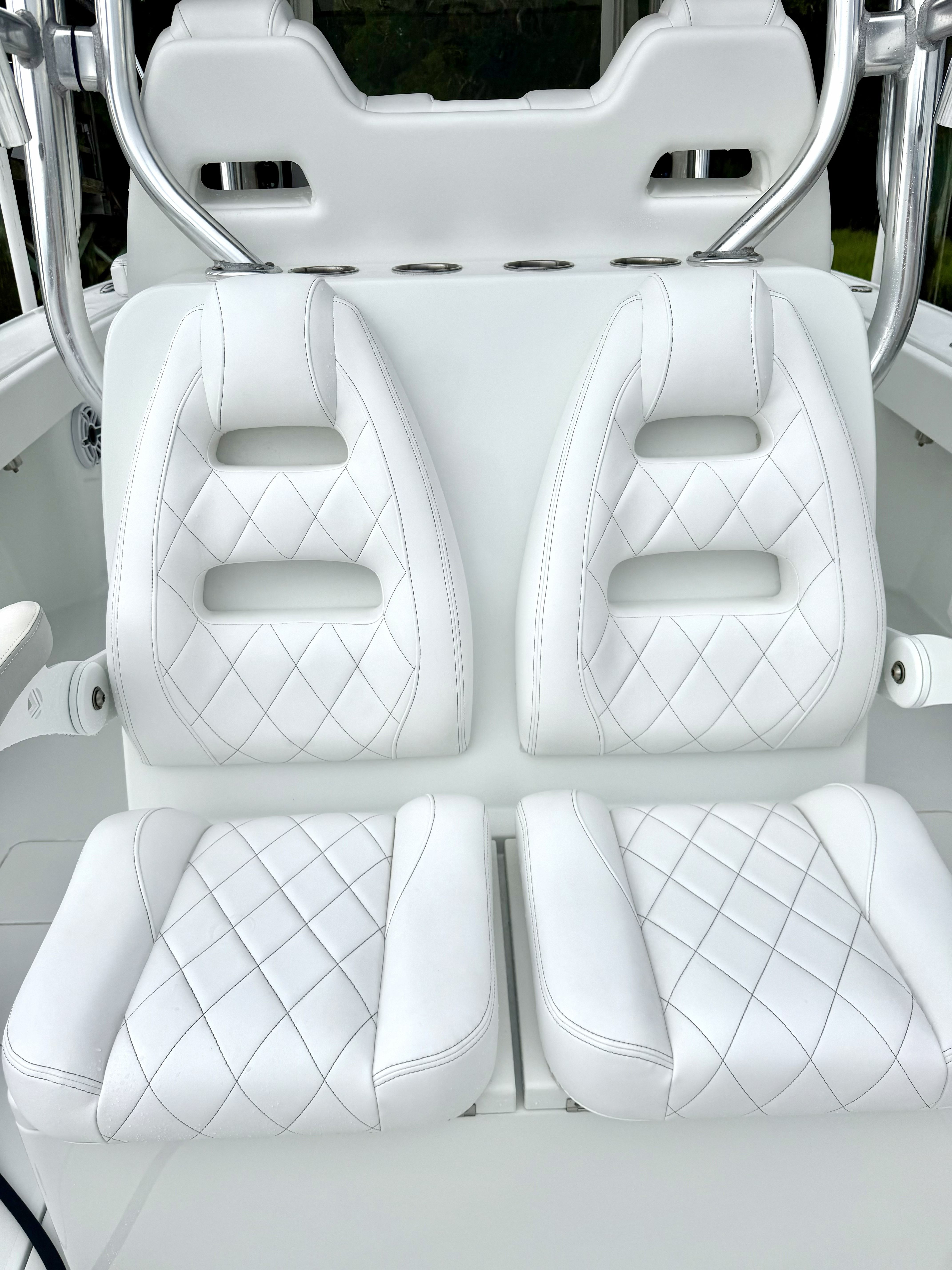 Two white, cushioned boat seats with quilted pattern and backrests.